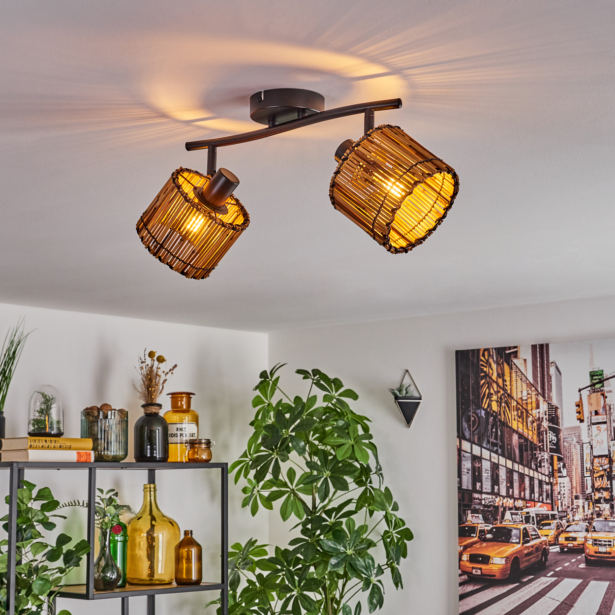 Zwei Bambuslampen an der Decke, die nach unten leuchten. Ein Regal mit Flaschen und einer Pflanze, und ein New York City Bild an der Wand.