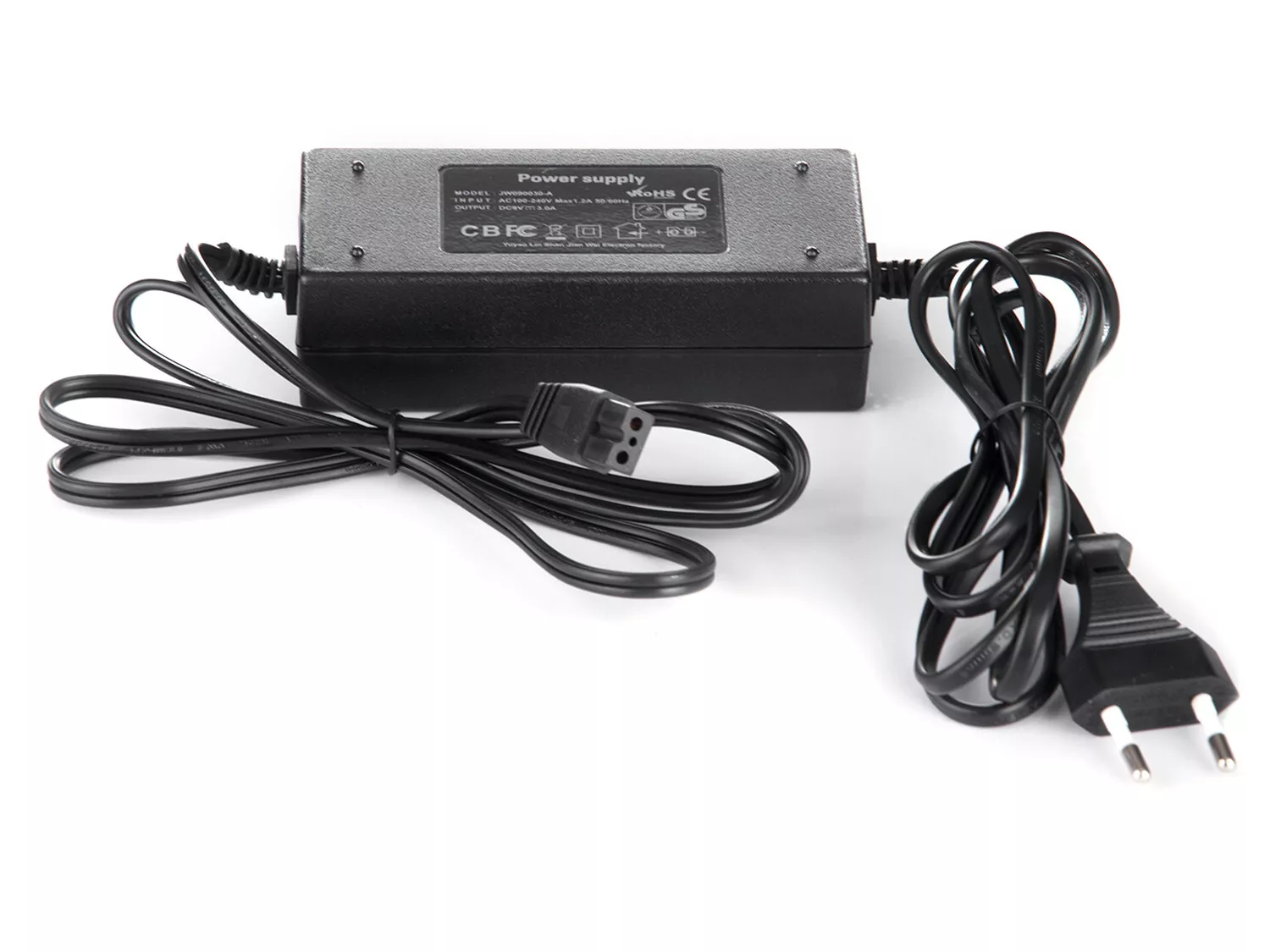 Czarny zasilacz z etykietą umieszczony na białej powierzchni. Posiada dwa czarne kable, jeden z wtyczką.