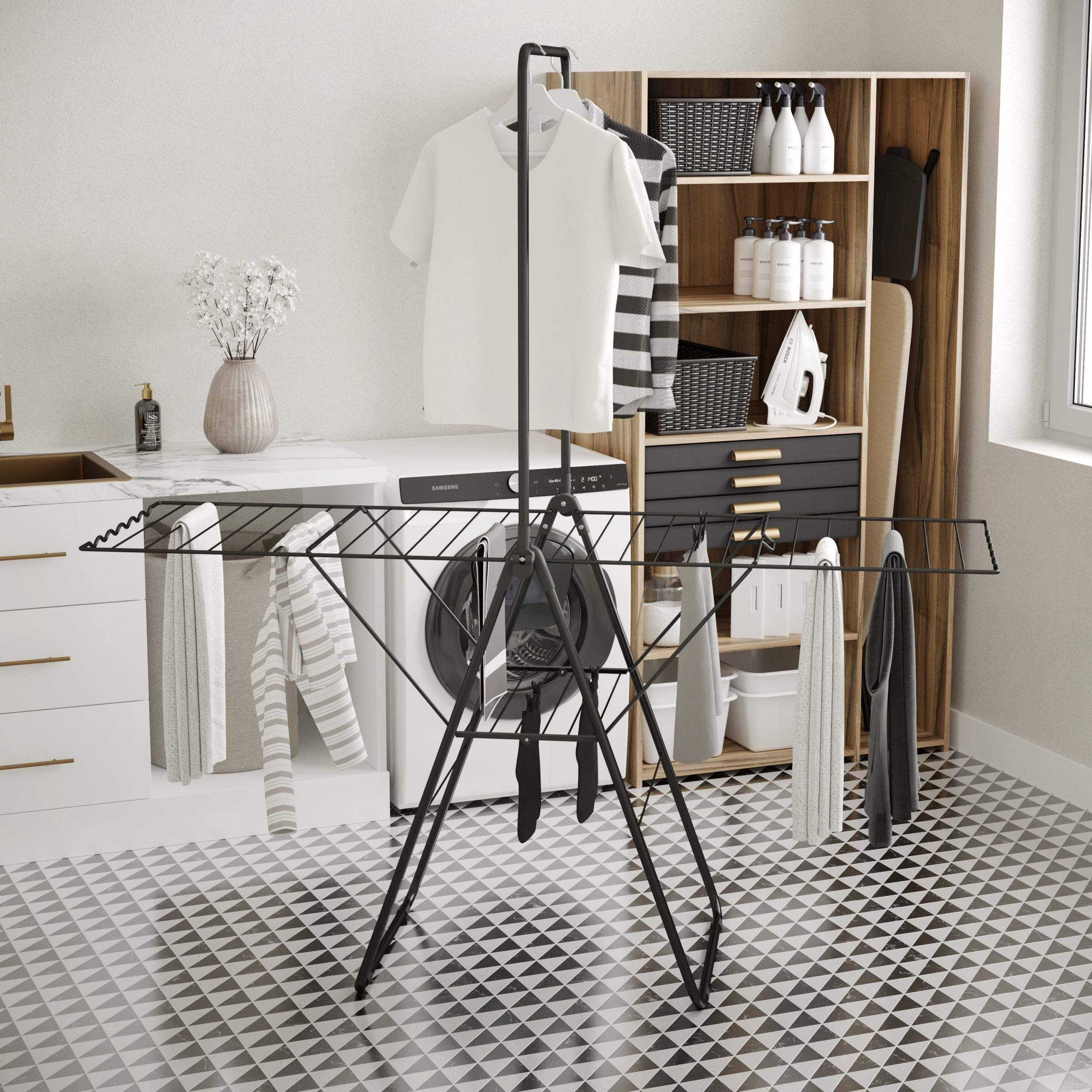 Laundry room with washing machine, drying rack, clothes, and wooden cabinet filled with cleaning supplies and an ironing board.