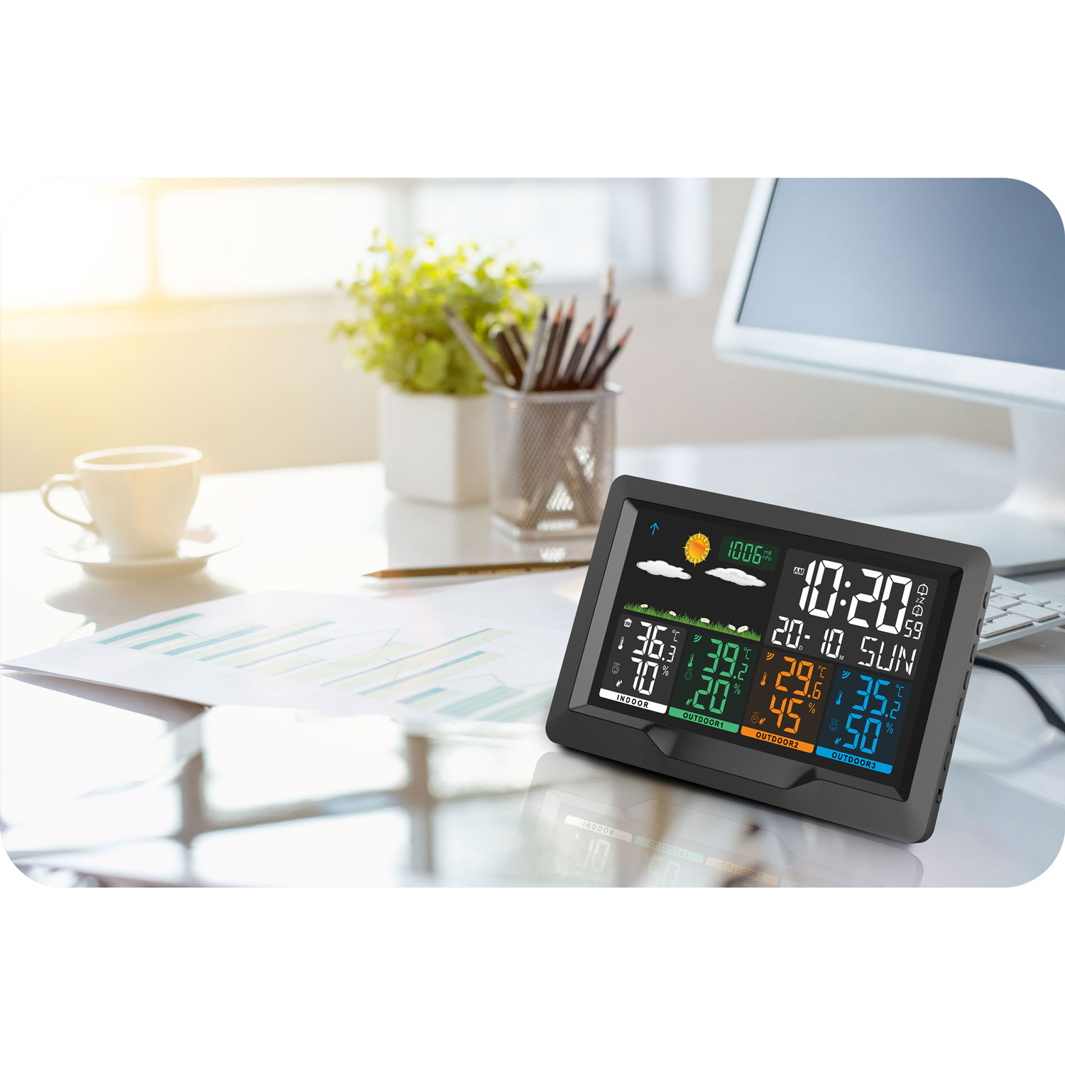Cyfrowa stacja pogodowa wyświetla temperaturę i czas na biurku. Obecny jest również kubek, rośliny, długopisy i papiery.