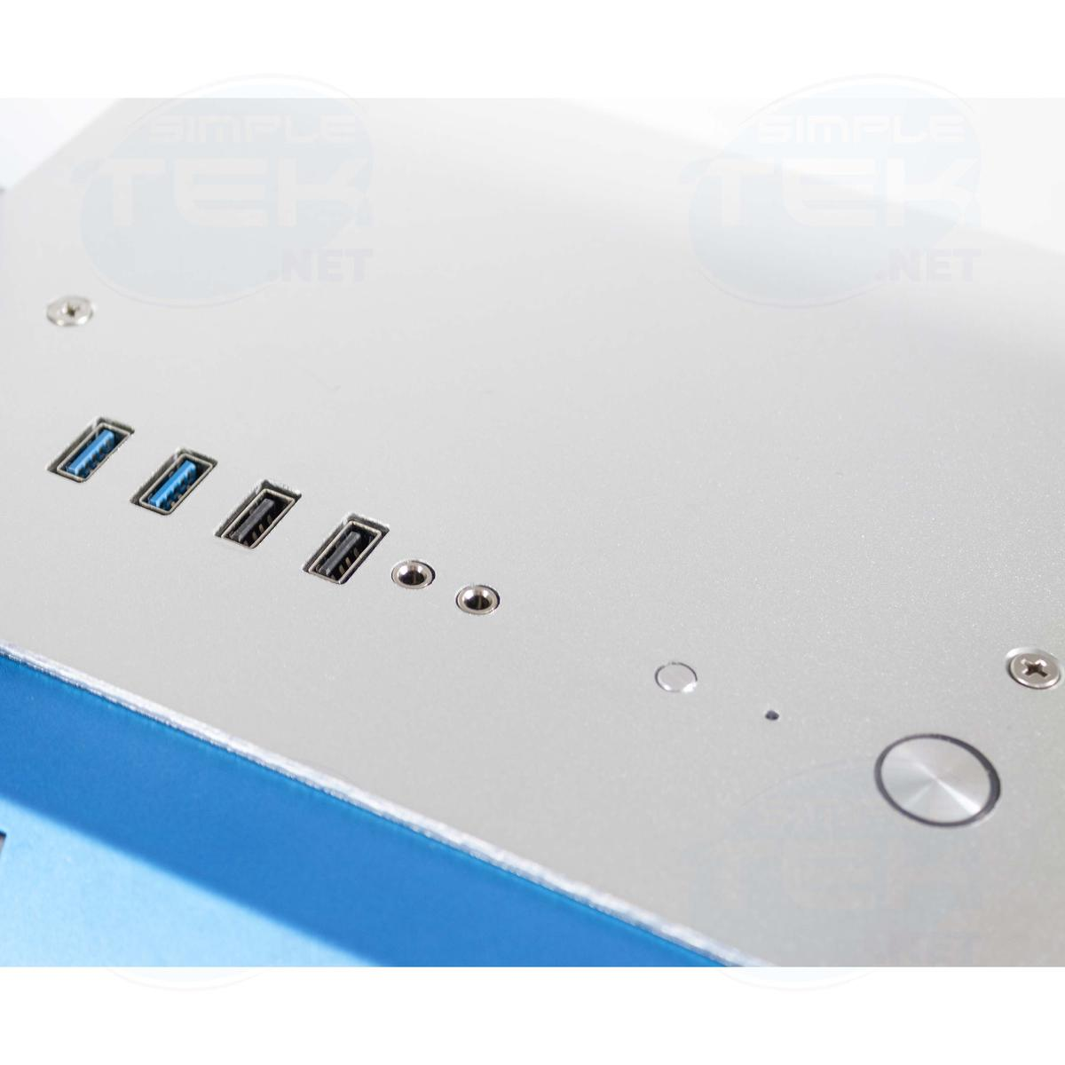 Vista ravvicinata di un case per computer con porte USB e pulsanti. Parte superiore in metallo argentato con bordo blu, varie porte visibili.