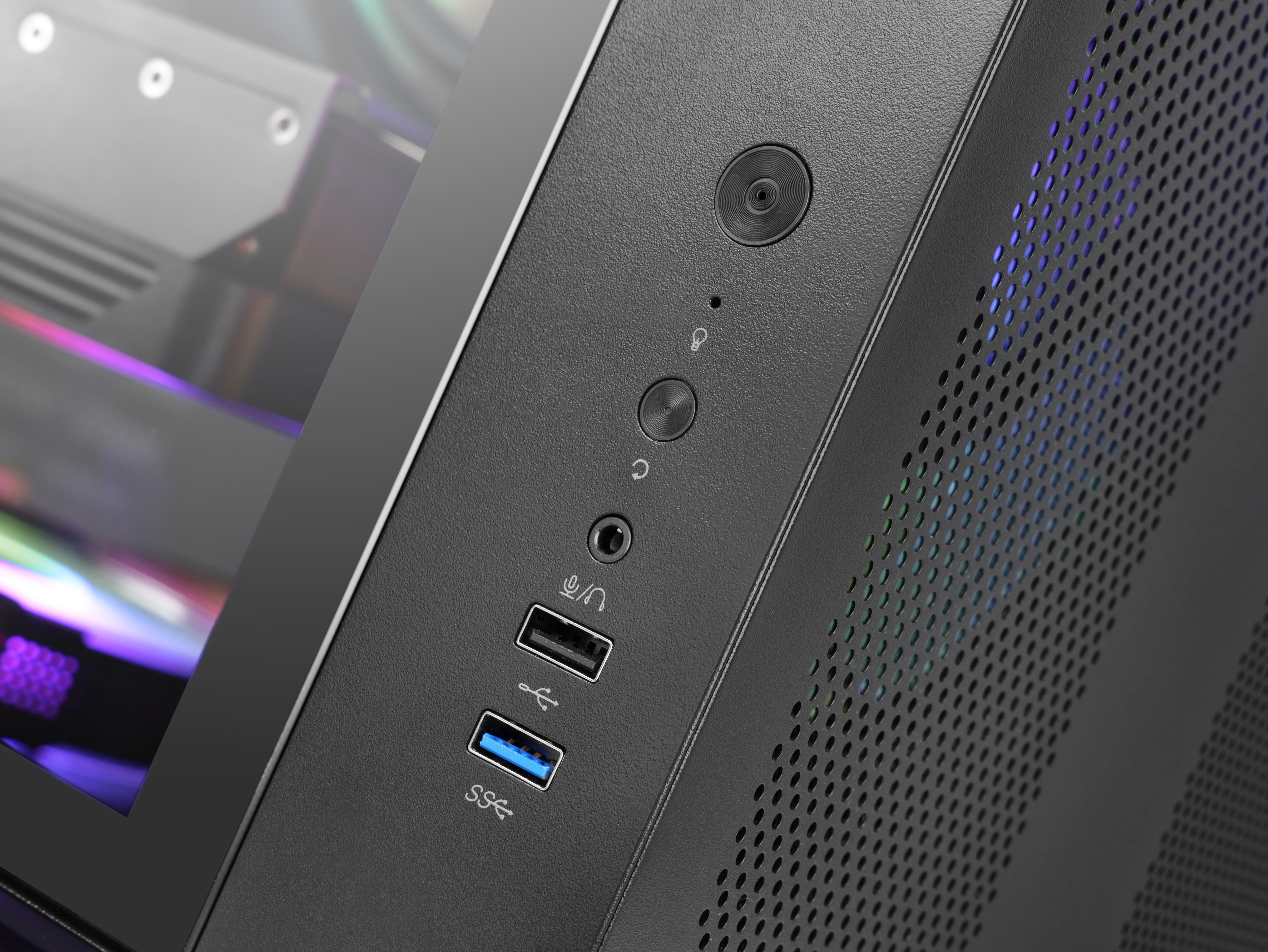 Zbliżenie czarnej obudowy komputera z przyciskami, portami i perforowanym panelem bocznym. Widoczny przycisk zasilania.