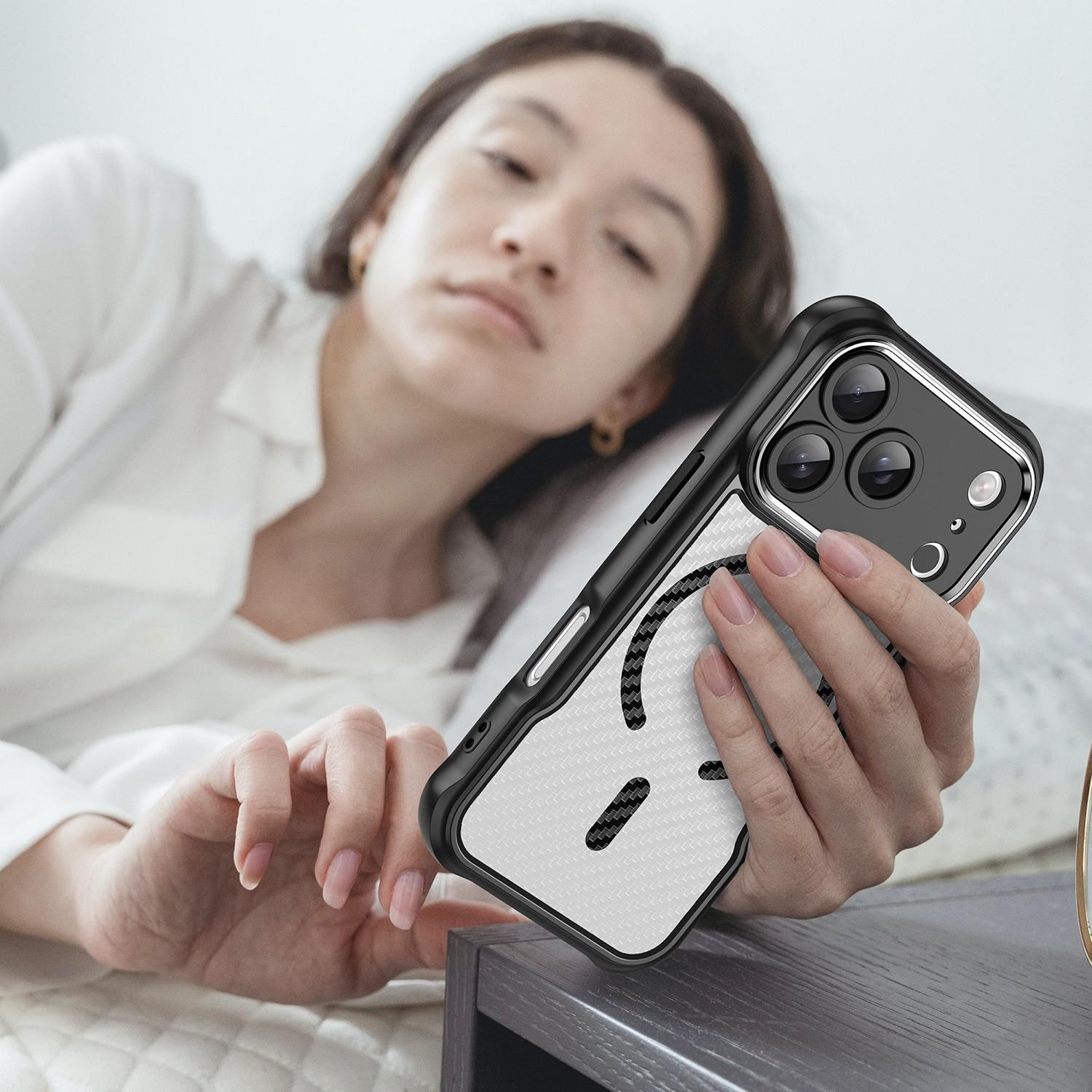 Eine Frau im Bett hält ein Smartphone mit einer einzigartigen Hülle. Die Handyhülle hat einen schwarzen Rand und eine weiße Rückseite mit Muster.