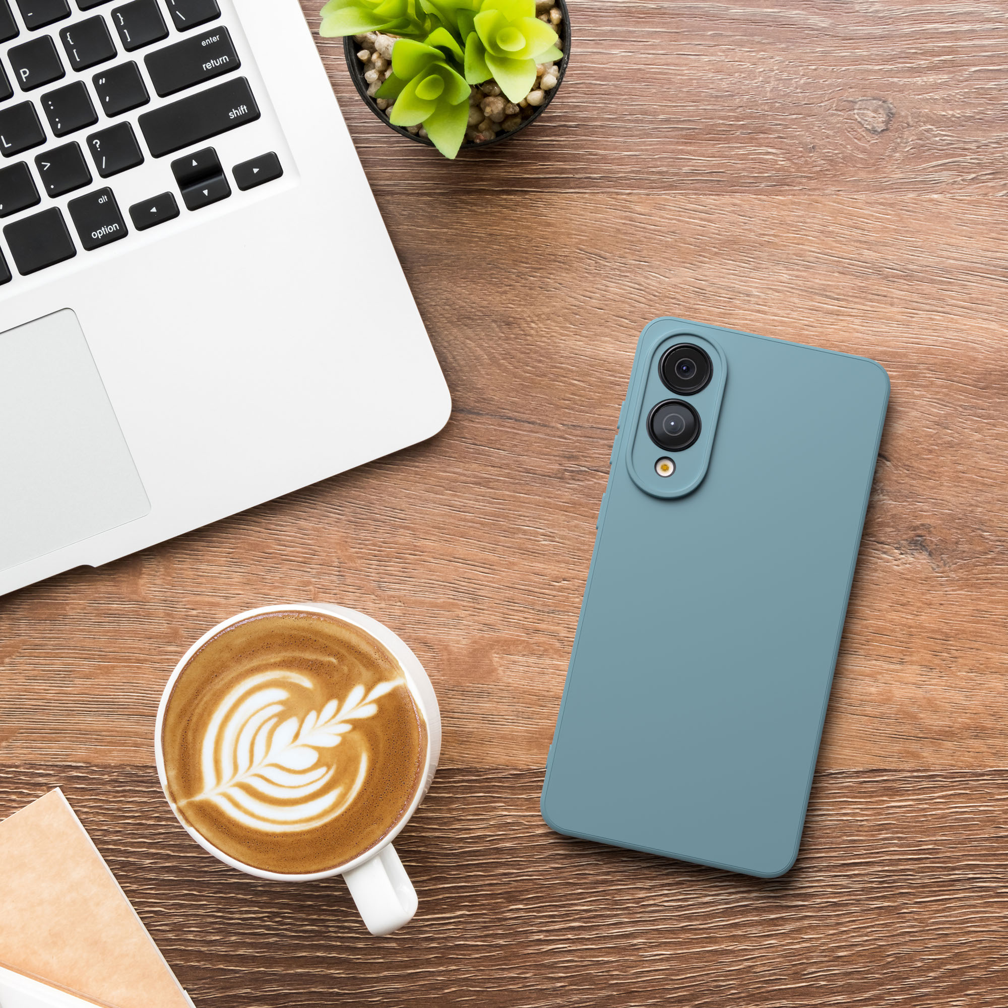 Holztisch mit Laptop, Kaffee, Telefon und Pflanze. Telefon ist blau. Kaffee hat Latte Art.