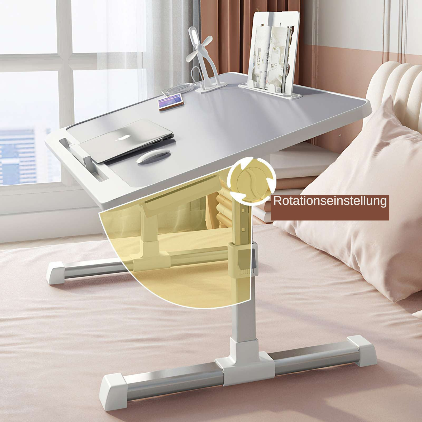 Ein weißer, verstellbarer Laptop-Schreibtisch mit Laptop, Tablet und Zubehör auf einem Bett. Der Schreibtisch steht am Fenster.