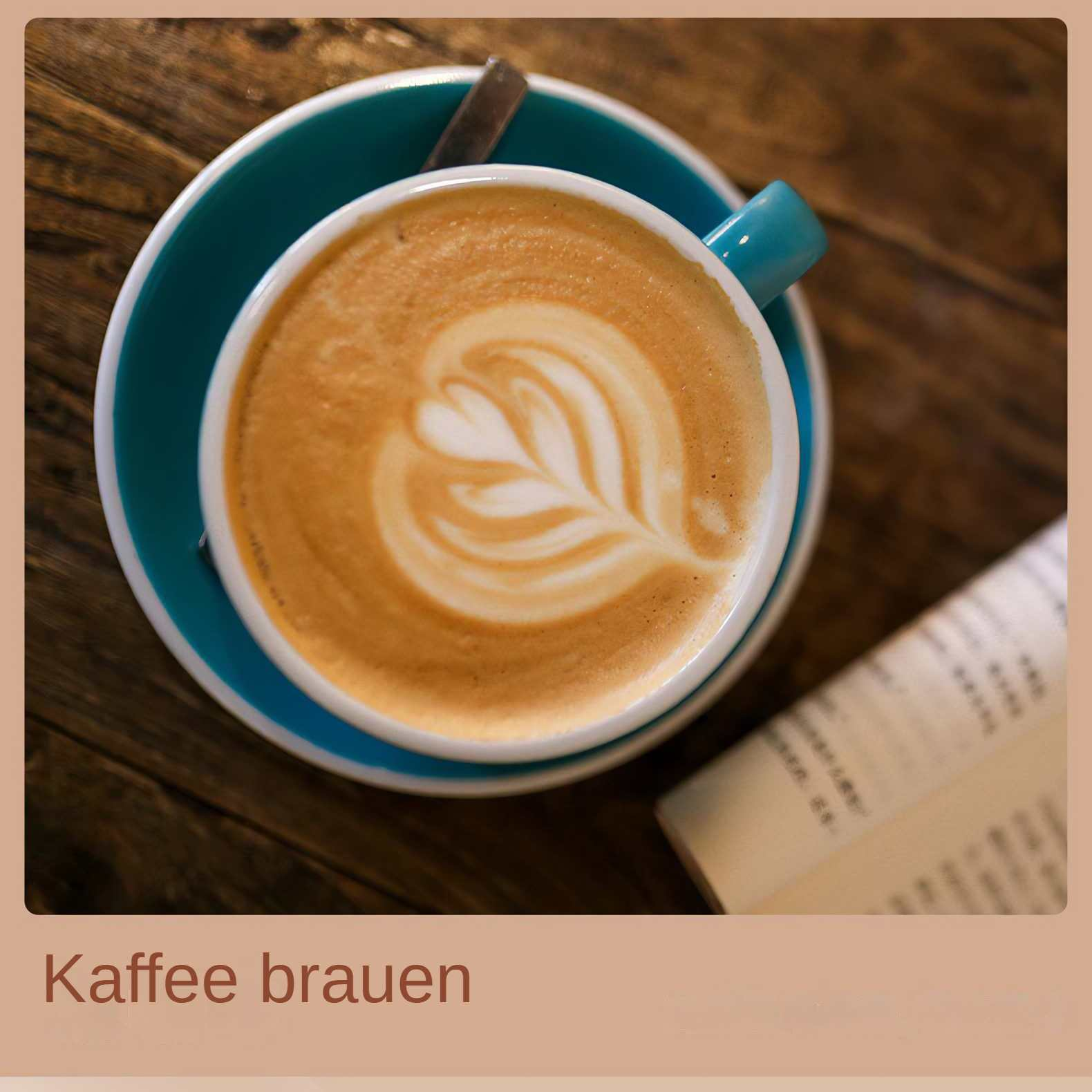 Eine Kaffeetasse mit Latte Art steht auf einer Untertasse neben einem Buch. Holztisch.
