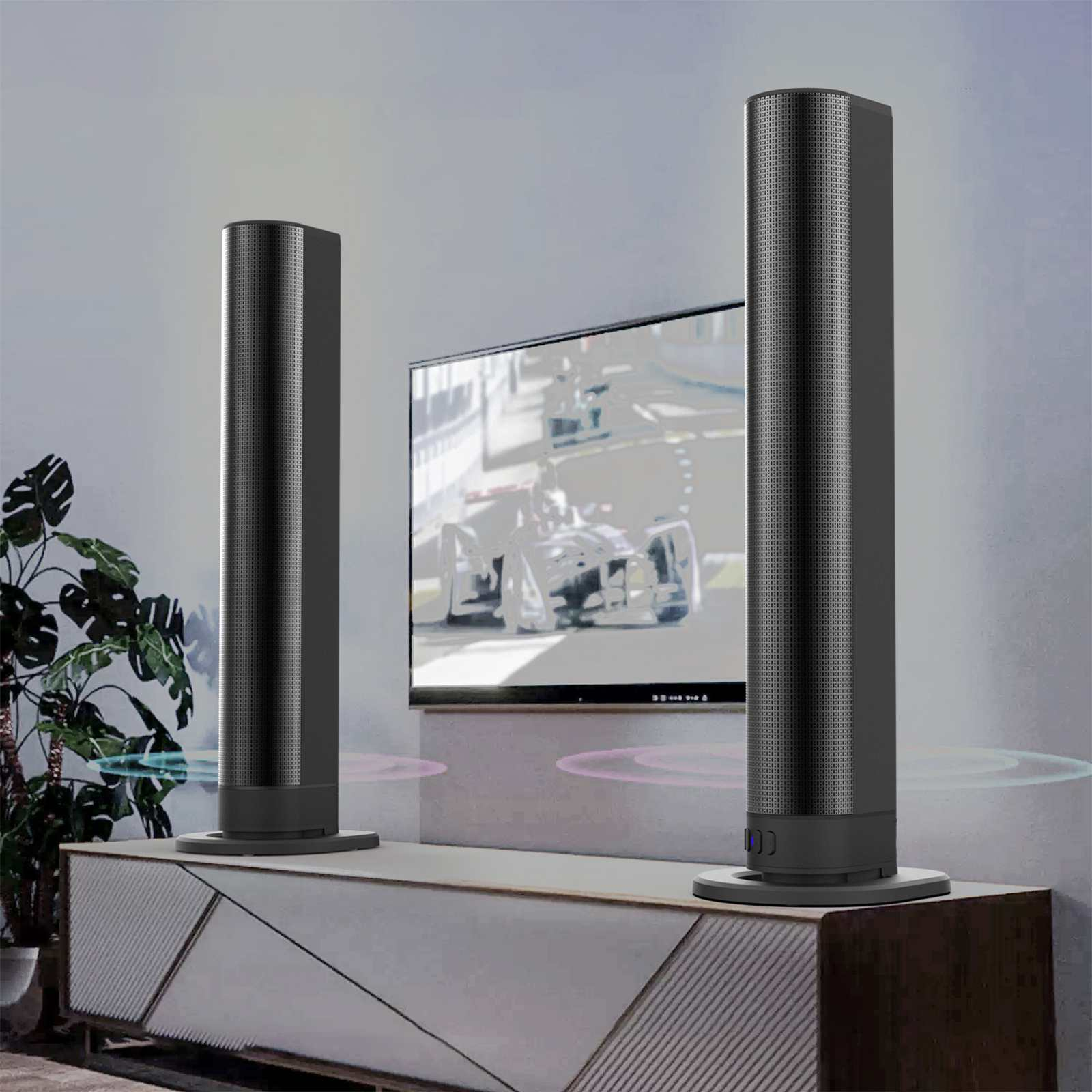 Zwei schwarze zylindrische Lautsprecher stehen auf einem weißen Schrank. Ein Fernseher zeigt eine verschwommene Rennszene.
