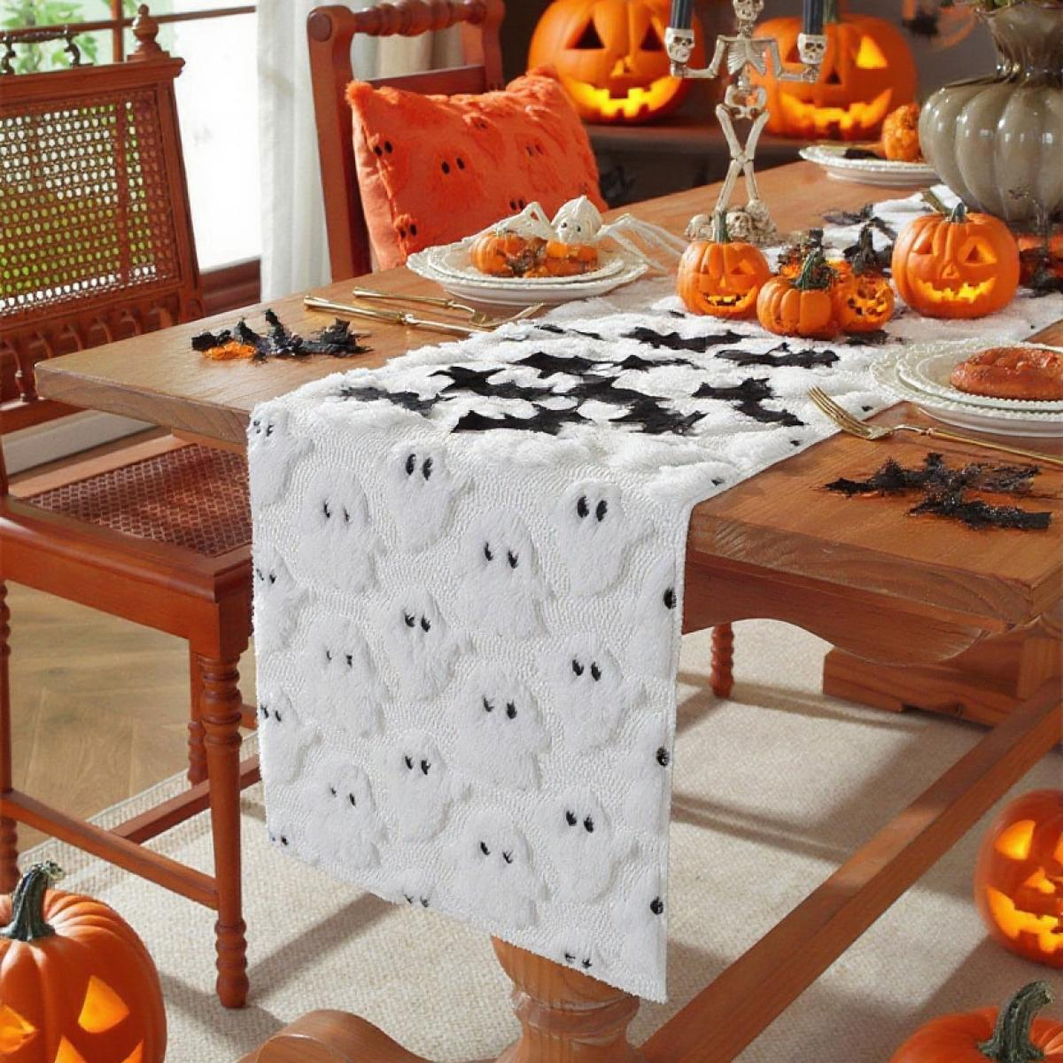 Halloween-Tischarrangement mit Kürbissen, Geister-Tischläufer und dekorativen Elementen. Holzstühle, orangefarbenes Kissen und beleuchtete Kürbisse.