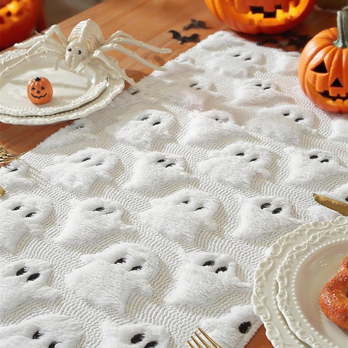 Halloween-Tischdeko mit geformtem Tischläufer, Kürbissen, Tellern, Spinne und kleiner Kürbis-Dekoration.