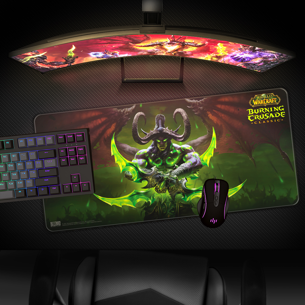 Configurazione di gioco con tappetino per mouse di World of Warcraft, tastiera e mouse. Un monitor curvo mostra una scena di gioco.