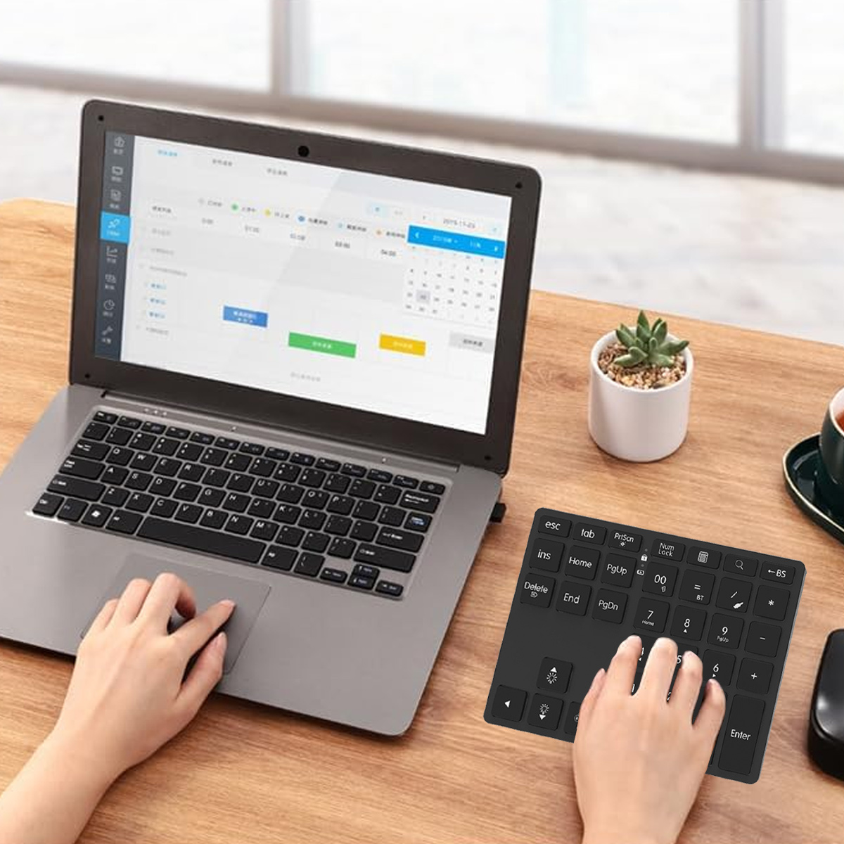 Eine Person, die einen Laptop und eine externe Tastatur auf einem Holztisch benutzt. Auf dem Laptop-Bildschirm wird ein Kalender angezeigt.