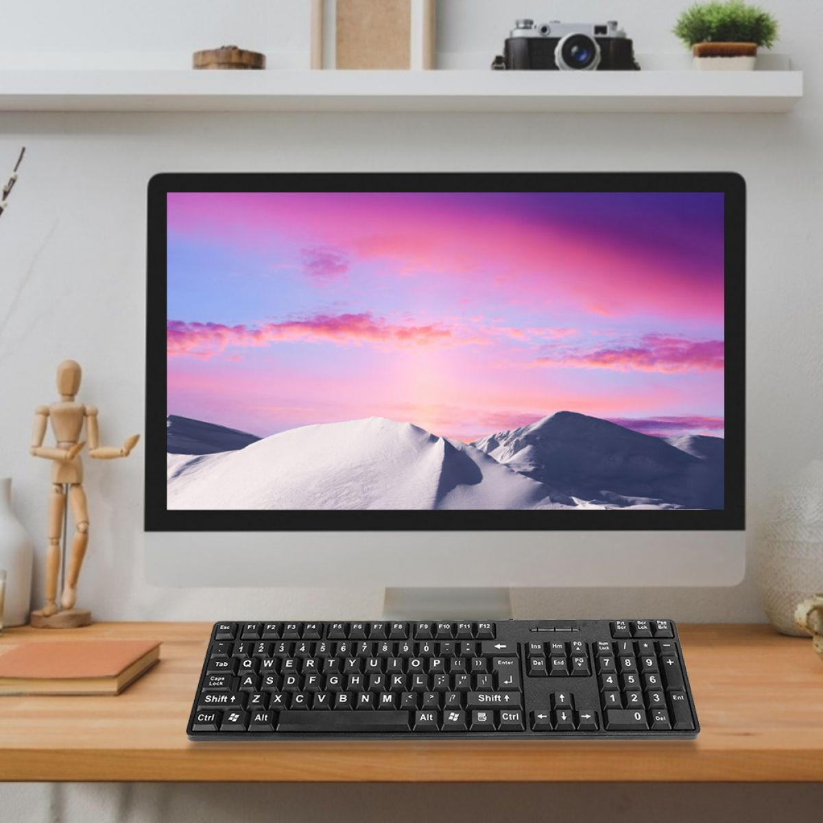 Ein Computer mit einer Berglandschaft auf dem Bildschirm. Vorne liegt eine schwarze Tastatur. Ein Holzschreibtisch und ein Regal sind im Hintergrund.