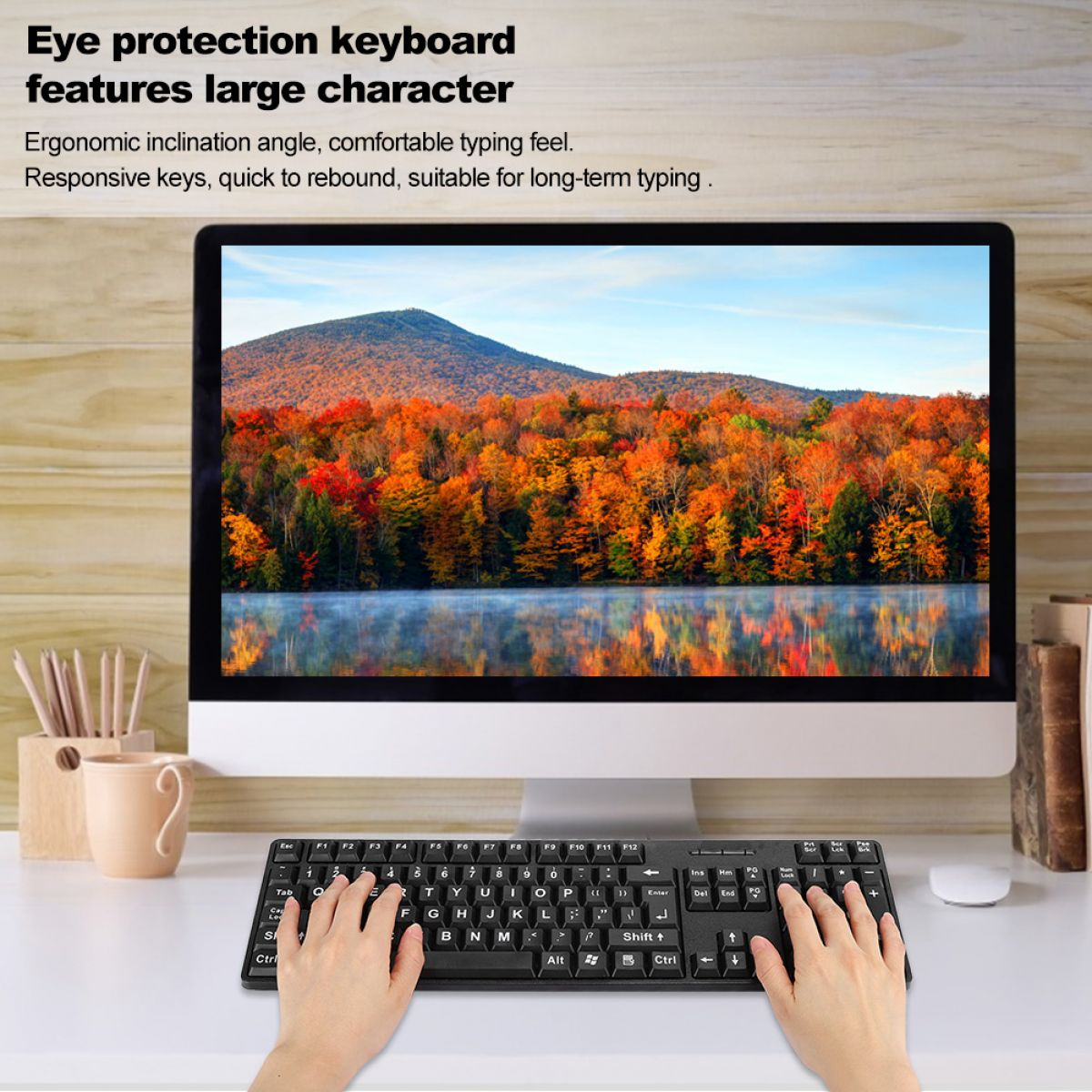 Eine Person tippt auf einer schwarzen Tastatur vor einem Computer, der eine bunte Herbstlandschaft zeigt. Hände auf der Tastatur.