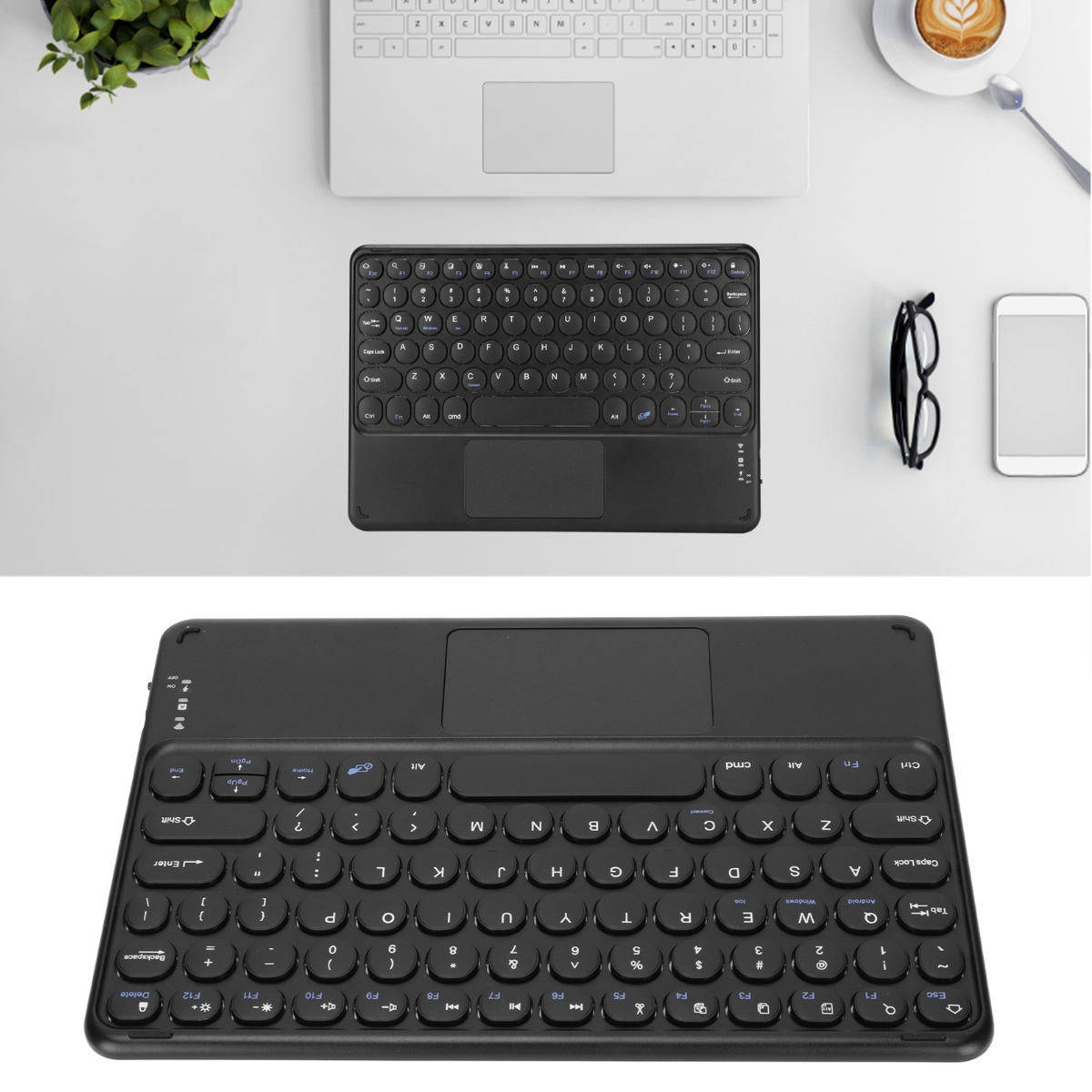 Schwarze Tastatur mit Touchpad, Laptop, Kaffee, Brille und Telefon auf weißer Oberfläche. Grüne Pflanze links.