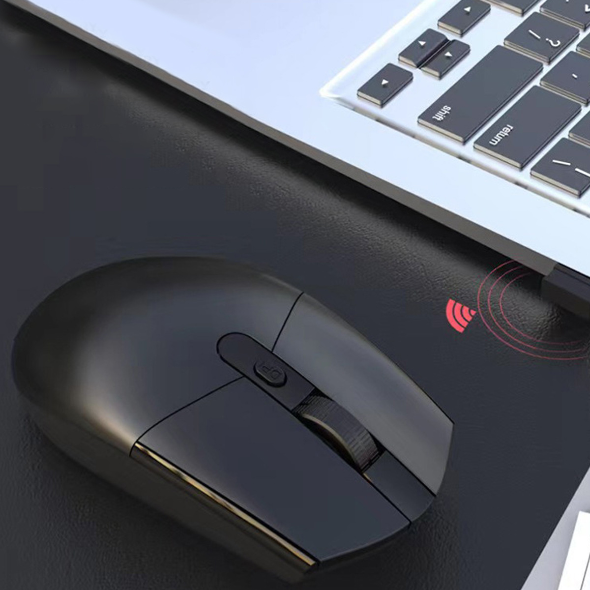 Eine schwarze kabellose Maus neben einer Laptop-Tastatur. Die Maus befindet sich auf einer schwarzen Oberfläche mit einem roten Funksymbol.