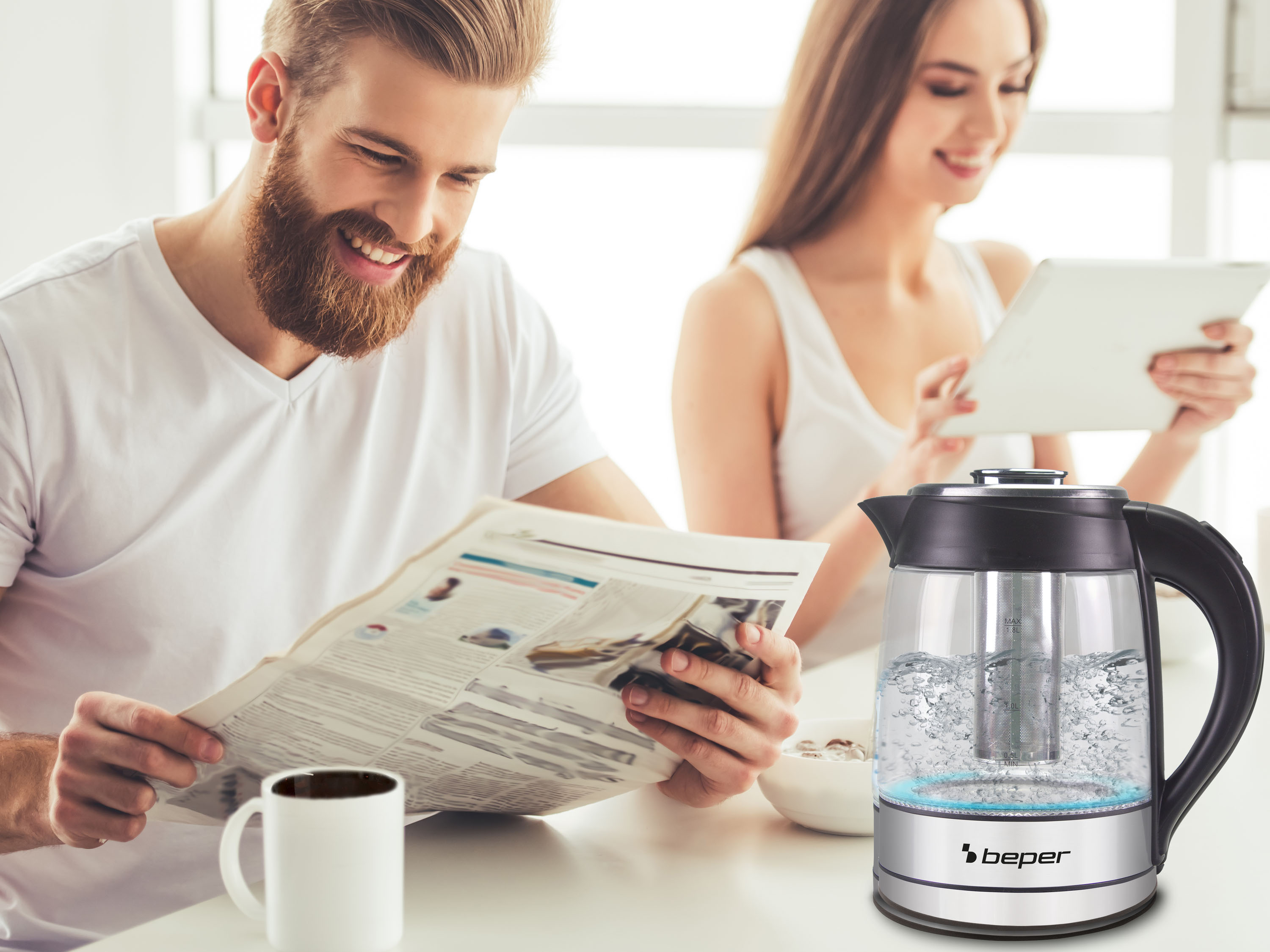 Mężczyzna czyta gazetę, kobieta korzysta z tabletu. Na stole stoi czajnik. Na stole stoi kubek kawy.