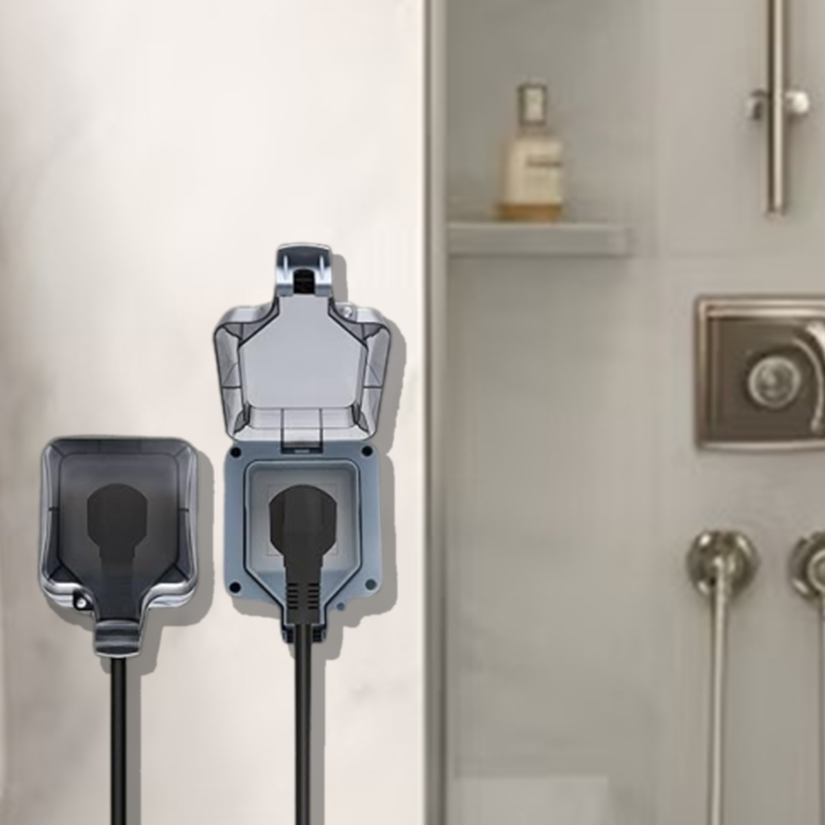 Zwei graue Steckdosen mit schwarzen Kabeln. Eine ist offen und zeigt den Stecker. Im Hintergrund sind eine Dusche und Toilettenartikel zu sehen.