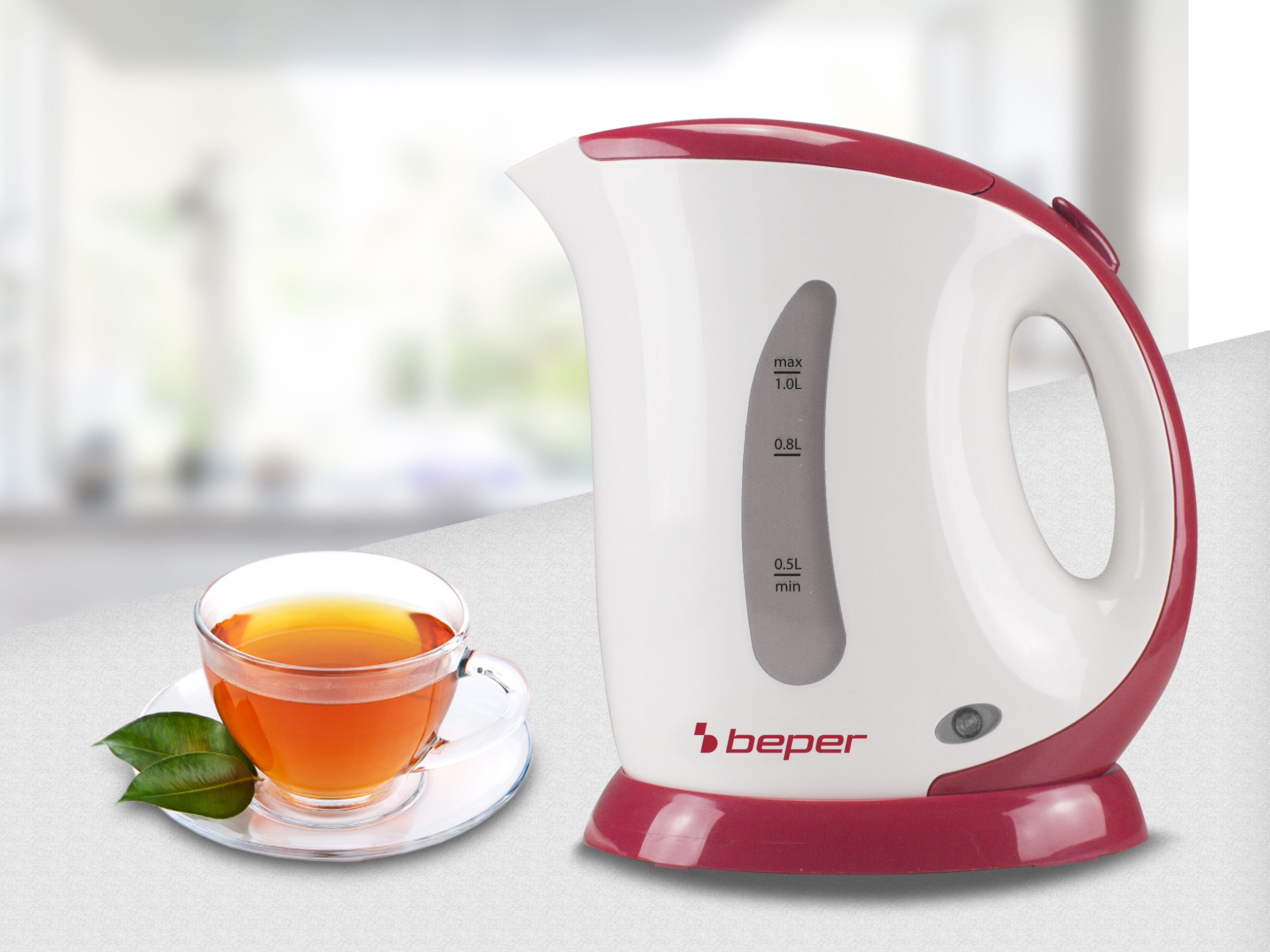 Bollitore elettrico bianco e rosso vicino a una tazza di tè con foglie su un piattino, su una superficie grigia.