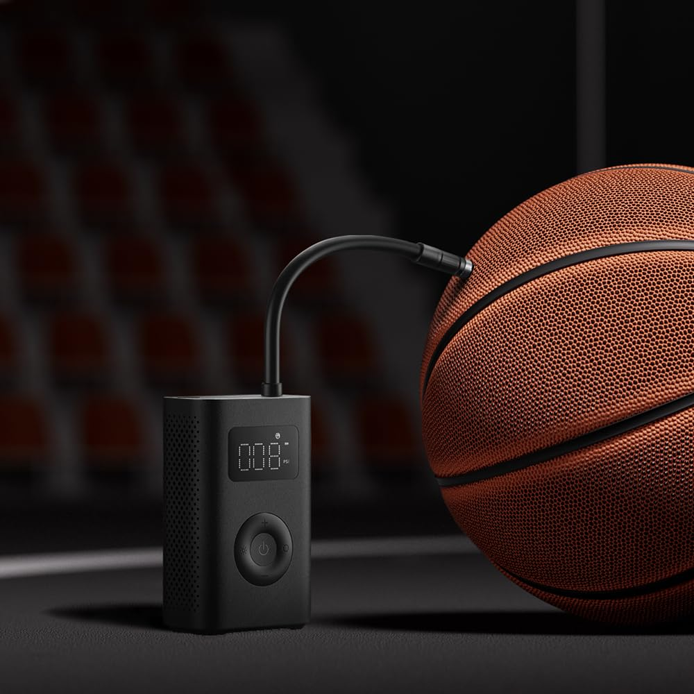 Eine schwarze Luftpumpe pumpt einen Basketball auf. Die Pumpe zeigt 0,08 an. Der Basketball ist braun mit schwarzen Linien, vor unscharfem Hintergrund.