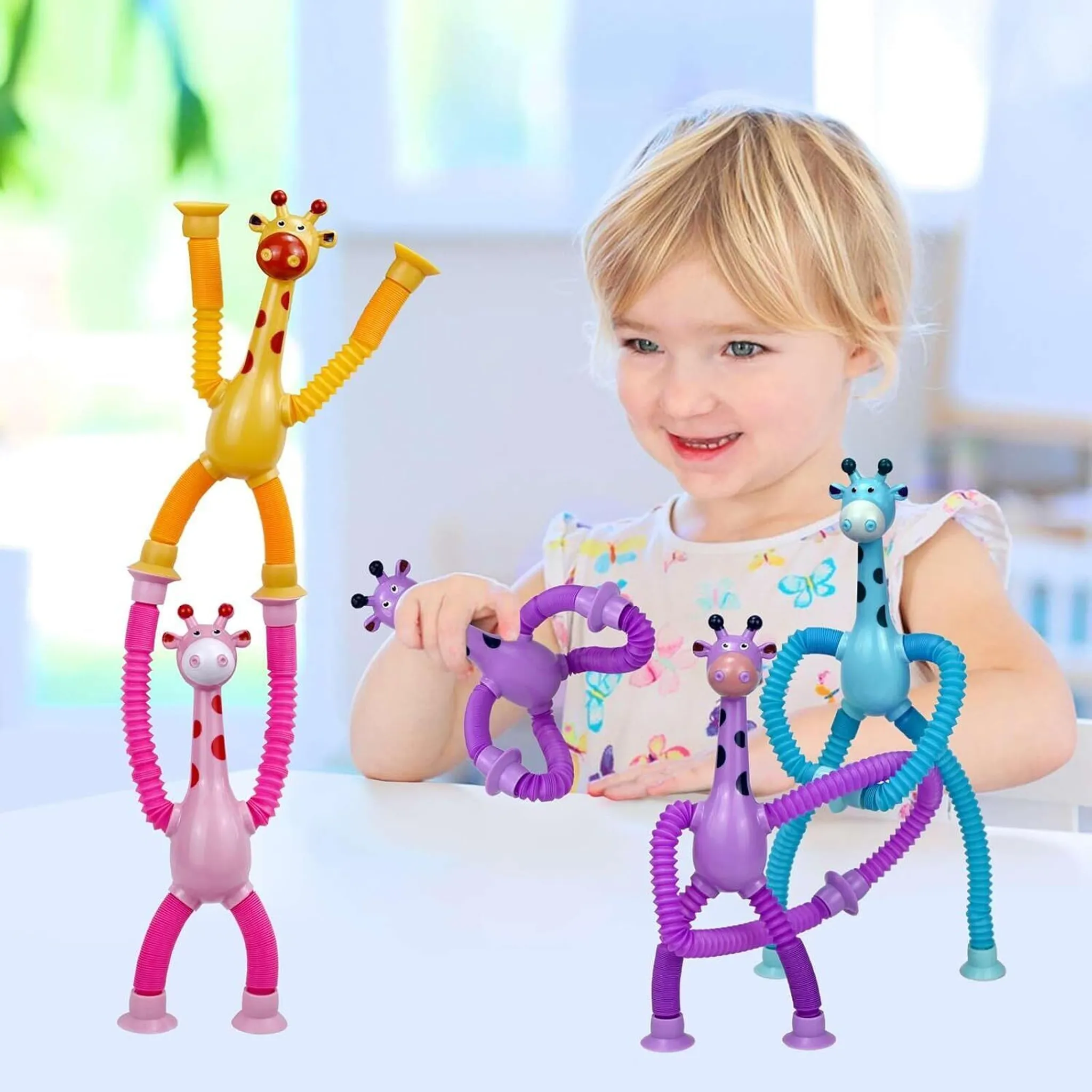 Ein Kind lächelt, während es mit bunten Giraffen-Spielzeugen spielt. Giraffen sind gelb, rosa, lila und blau mit biegsamen Beinen.