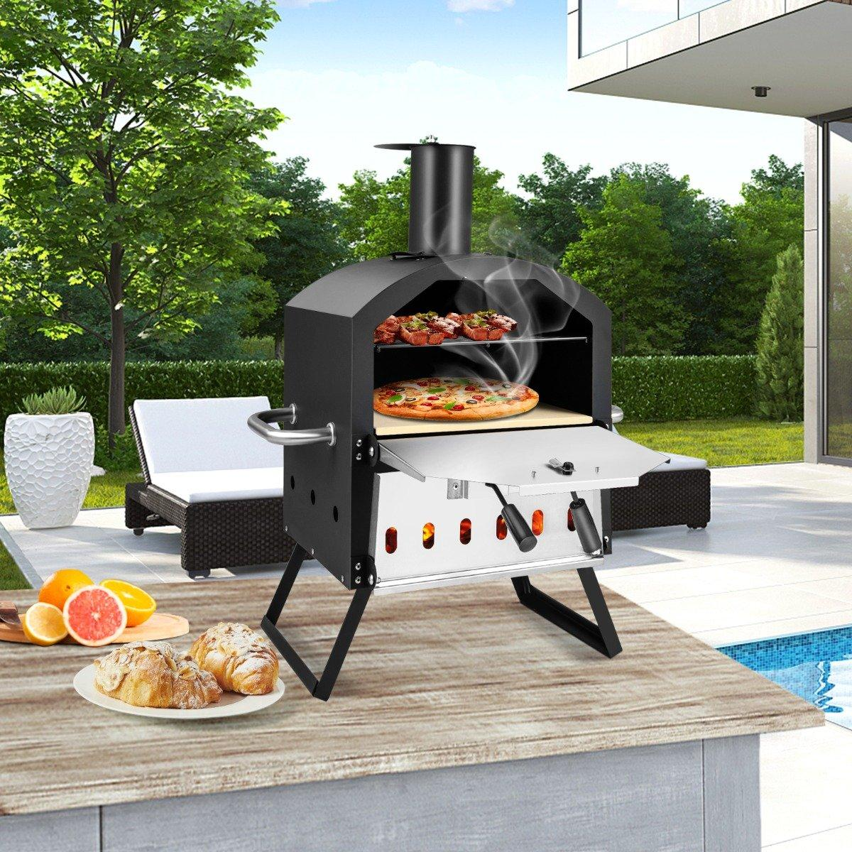 Horno de pizza al aire libre con pizza dentro. Frutas y pasteles en una mesa al frente. Piscina y árboles al fondo.