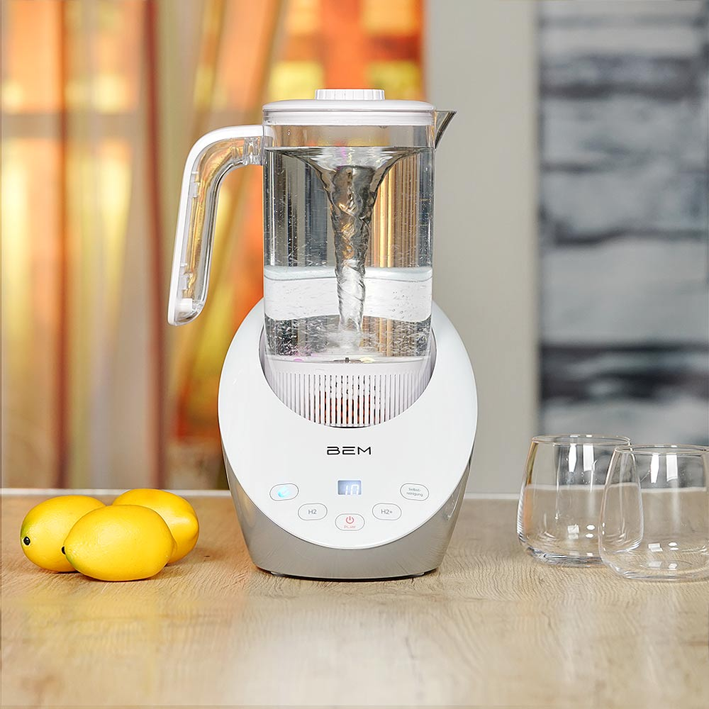 Ein Wasserreiniger mit Wasserwirbel, Zitronen und Gläsern stehen auf einem Holztisch. Der Hintergrund hat einen Vorhang und eine Wand.