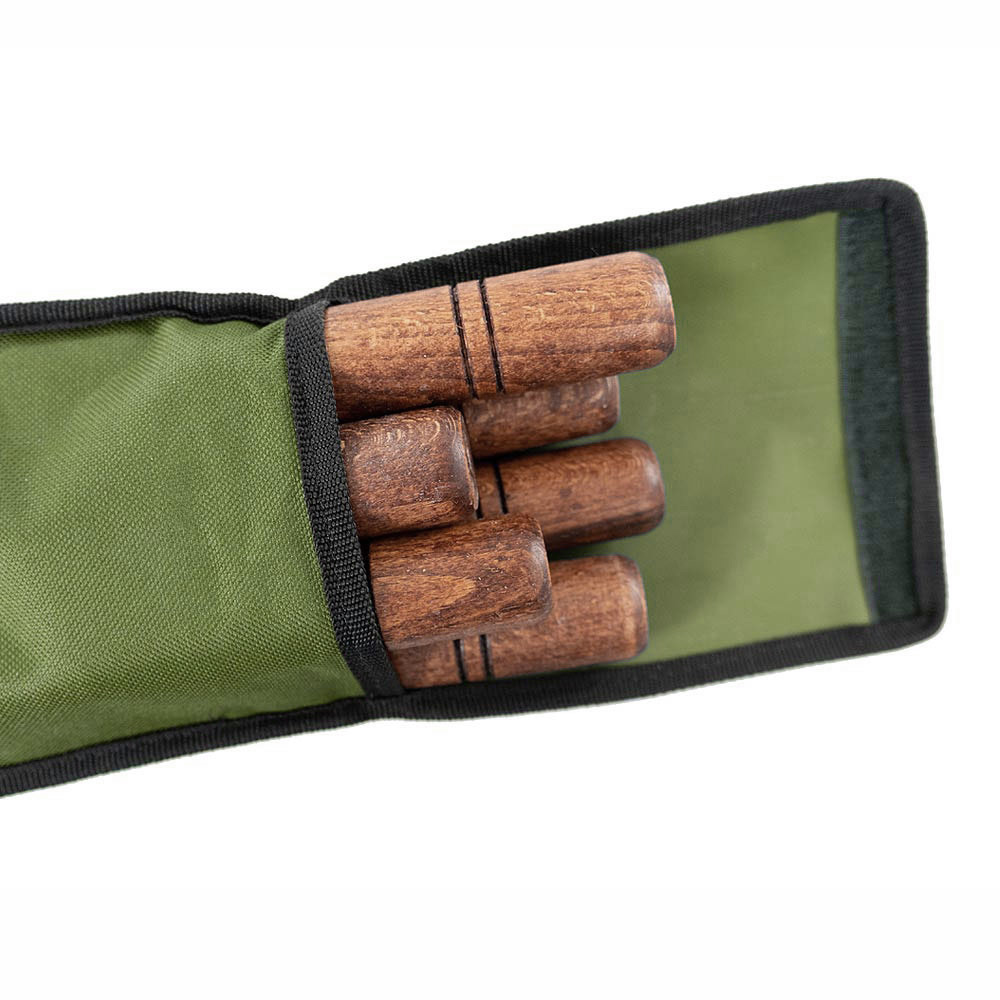 Holzstäbe teilweise in einem grünen Beutel mit schwarzem Rand. Stäbe sind braun mit Rillen. Beutel ist offen.