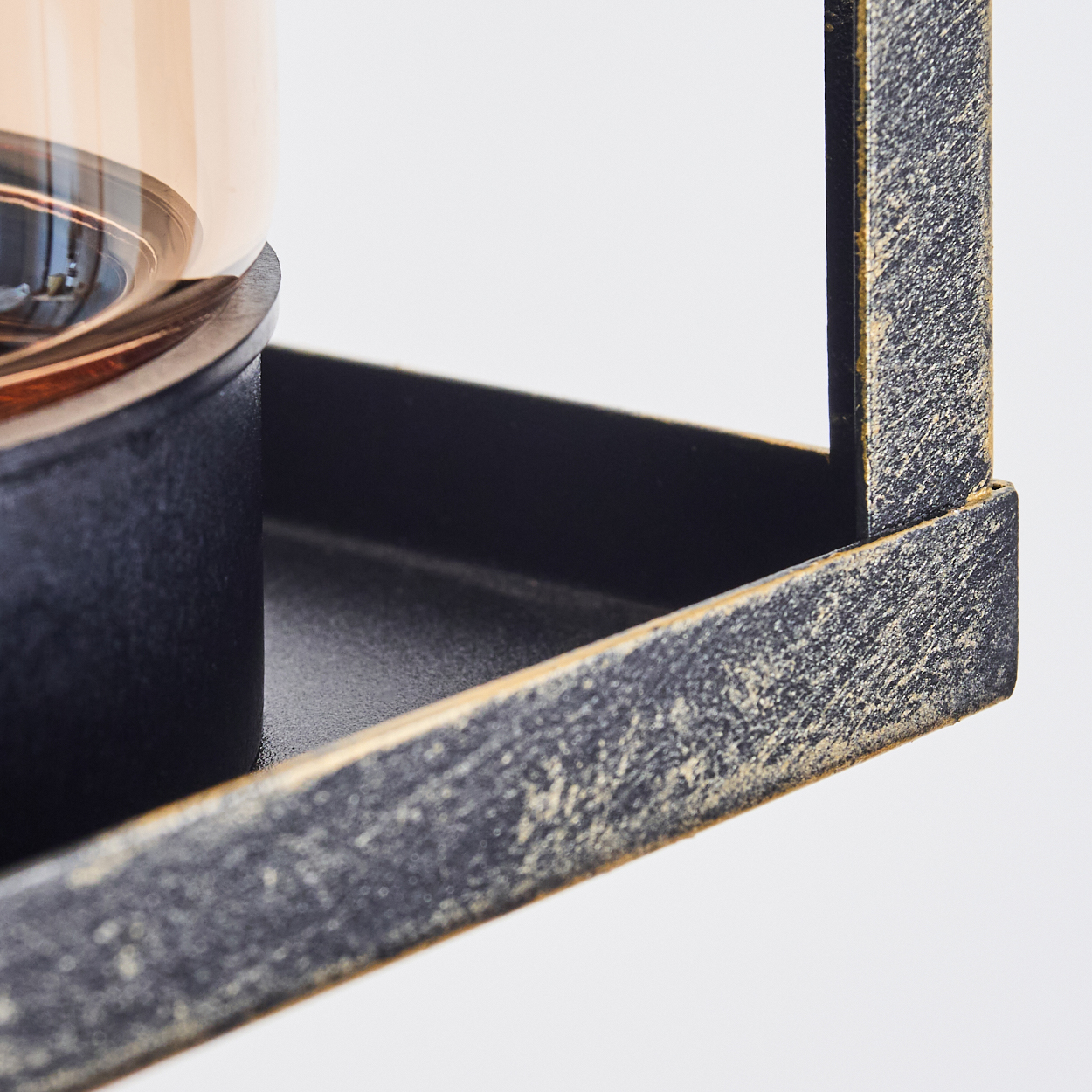 Nahaufnahme einer dekorativen Laterne. Sie hat einen schwarzen Metallrahmen mit goldenen Akzenten. Im Inneren ist ein Glaszylinder sichtbar.