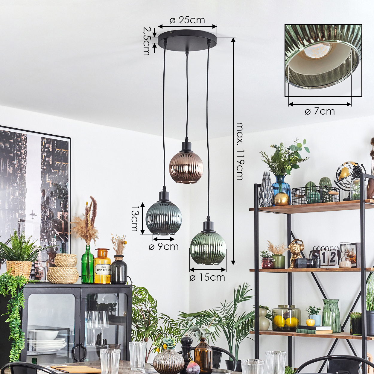 Drei Pendelleuchten hängen von der Decke. Die Lampen haben Glasschirme in verschiedenen Farben mit beschrifteten Abmessungen. Ein Regal mit Pflanzen und Deko.