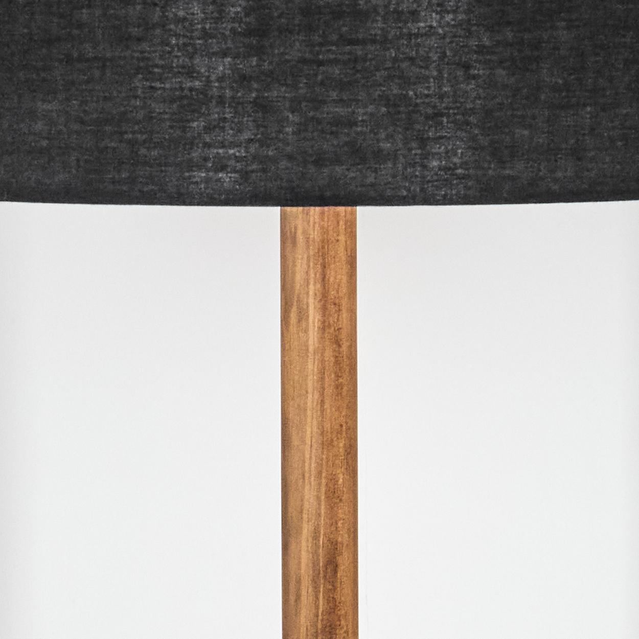 Eine Lampe mit einem dunkelgrauen Schirm steht auf einem Holzpfosten. Der Hintergrund ist schlicht weiß.