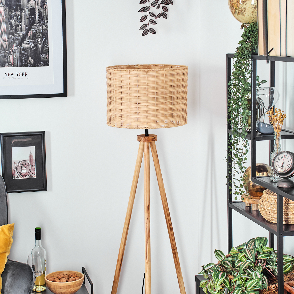 Ein Raum mit einer Holzstativlampe, Regalen mit Dekoration, Bildern und einer Schüssel mit Nüssen. Auf dem obersten Regal steht ein Globus.