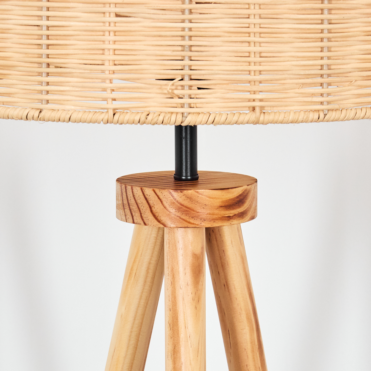 Eine Lampe mit gewebtem Lampenschirm und Holzfuß. Der Fuß hat ein Stativ-Design, und der Lampenschirm ist beige.
