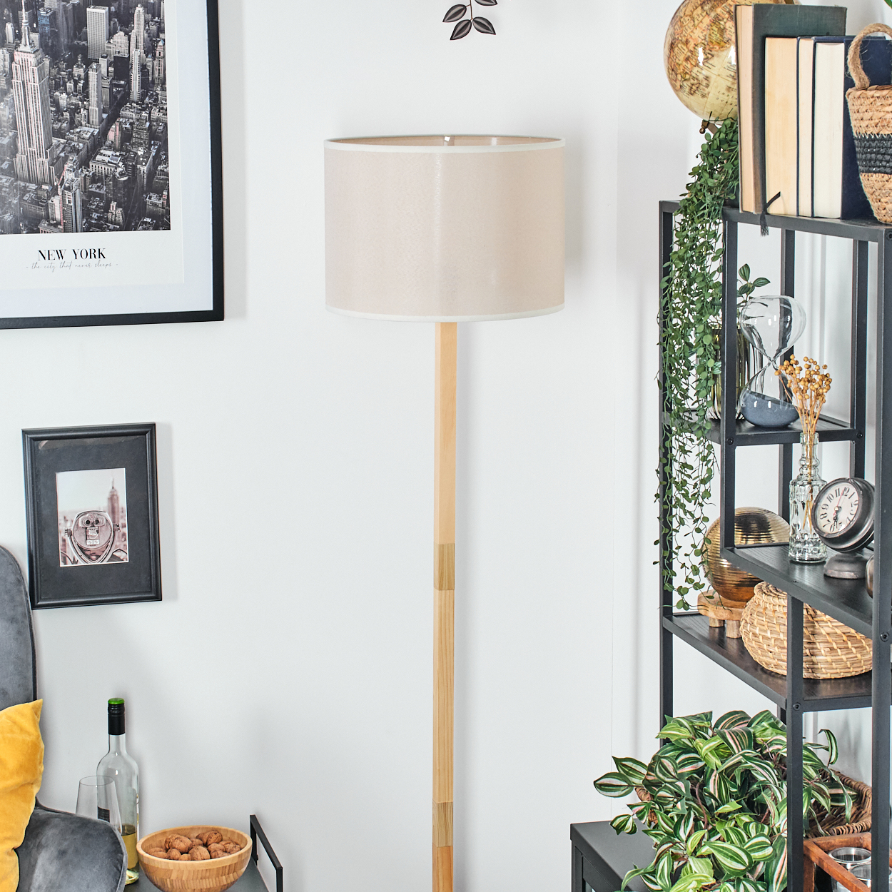Ein Raum mit einer Holzlampe, Regalen mit Gegenständen und gerahmten Bildern an der Wand. Eine Schüssel mit Walnüssen und Wein steht auf einem Beistelltisch.