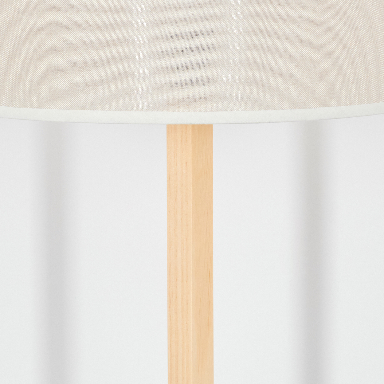 Nahaufnahme einer Lampe. Der Lampenschirm ist beige, die Holzstütze hellbraun und der Hintergrund weiß.