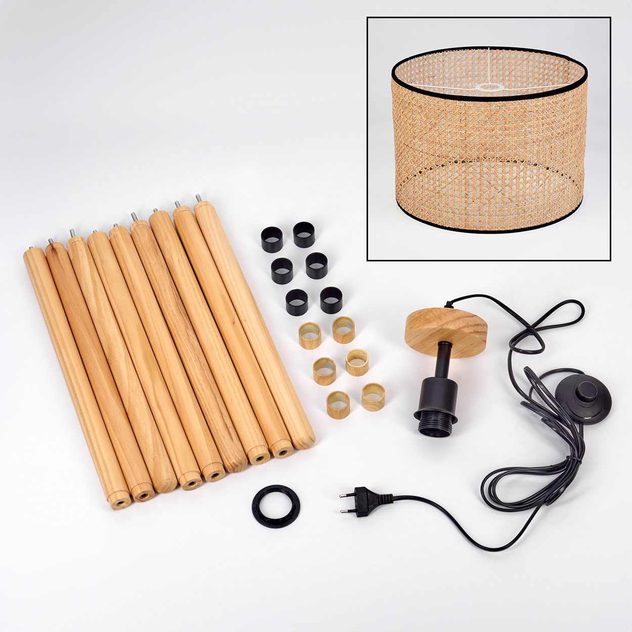 Zerlegte Lampe: Holzbeine, Rattanschatten, schwarze Ringe, Holzsockel mit Fassung und Netzkabel mit Stecker.