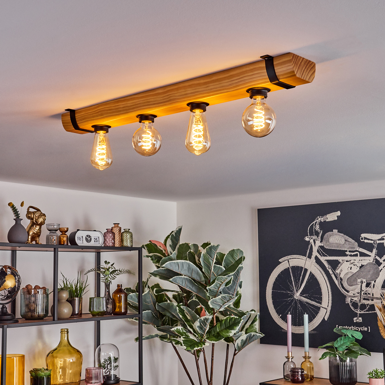 Ein Holzbalken mit vier hängenden Glühbirnen. Regale mit Dekor und eine große Pflanze darunter. Ein Motorrad-Kunstwerk im Hintergrund.