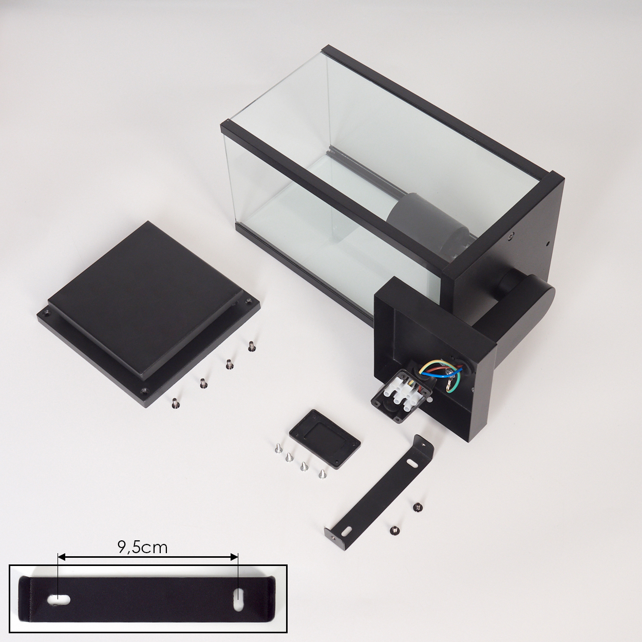 Zerlegte schwarze rechteckige Außenlampe mit Glasscheiben, Schrauben und Halterung auf weißer Oberfläche, 9,5 cm Halterung.