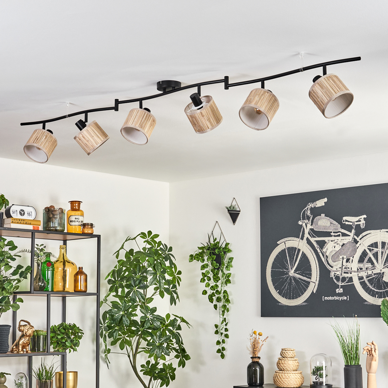 Deckenleuchten mit gewebten Schirmen. Im Hintergrund ein Fahrradkunstwerk und Pflanzen. Links sind Regale zu sehen.