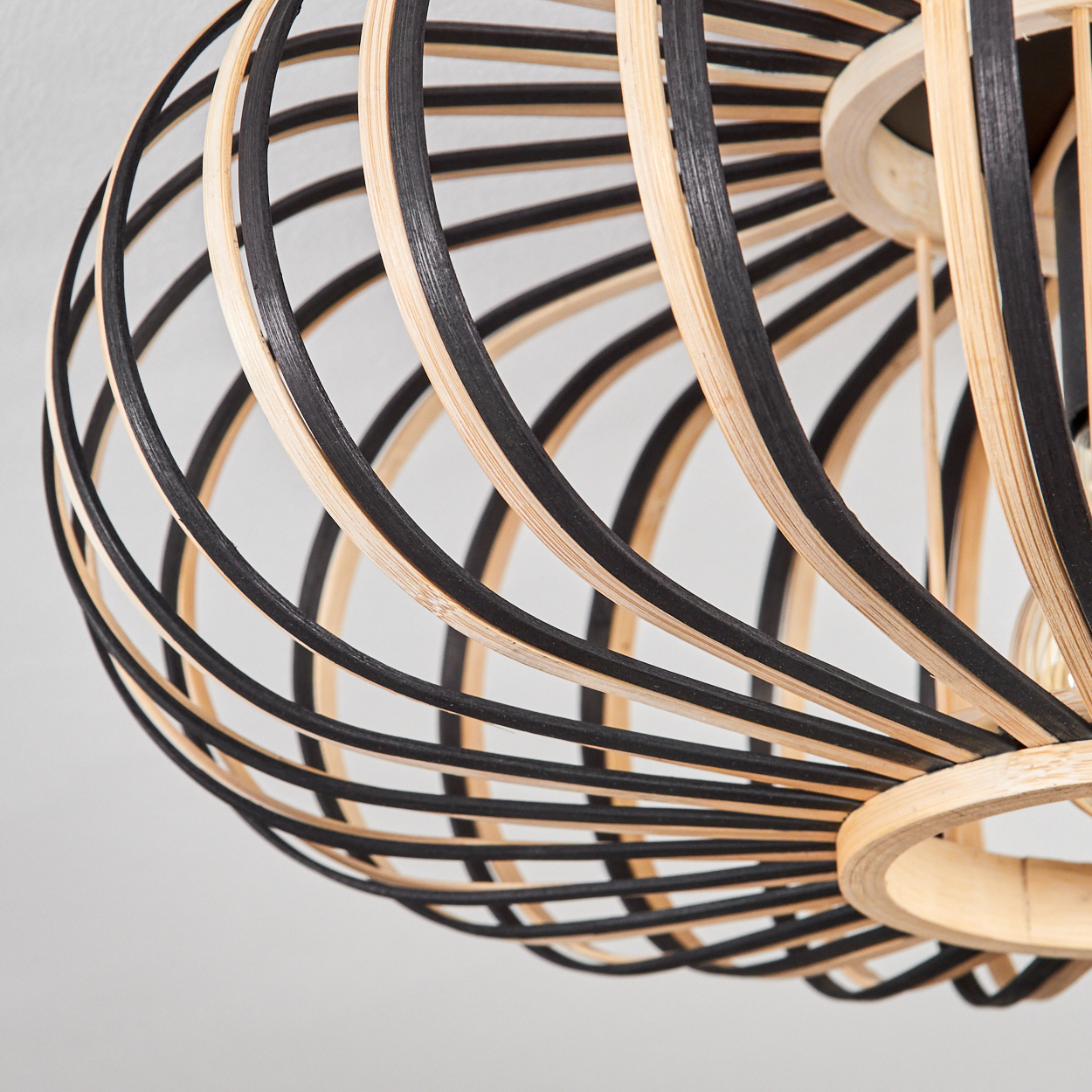 Nahaufnahme einer dekorativen Lampe, gefertigt aus abwechselnd schwarzen und natürlichen Holzstreifen, vor weißem Hintergrund.