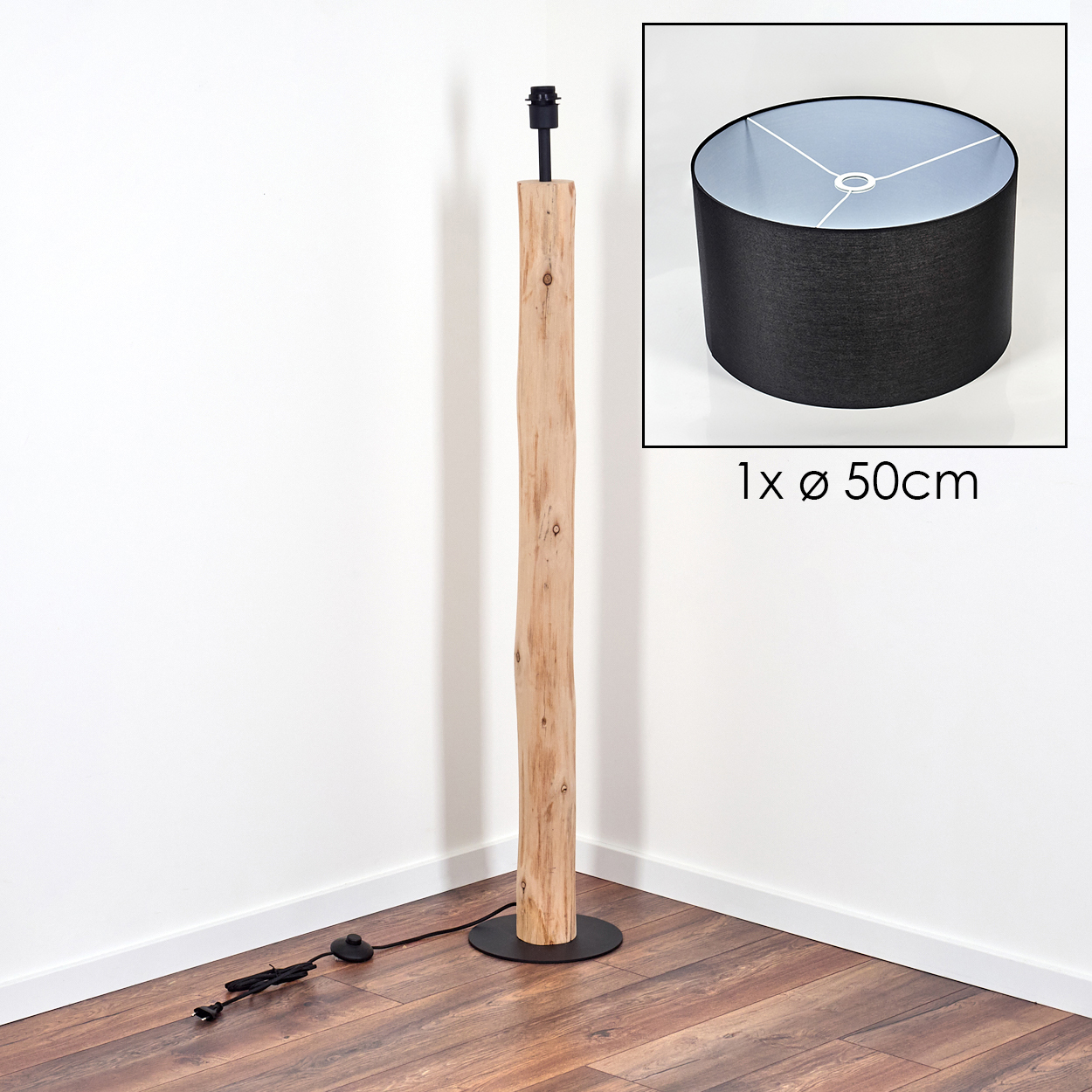 Eine Stehlampe steht in einer Ecke. Sie hat einen Holzpfosten, einen schwarzen Sockel und einen Lampenschirm mit 50 cm Durchmesser.