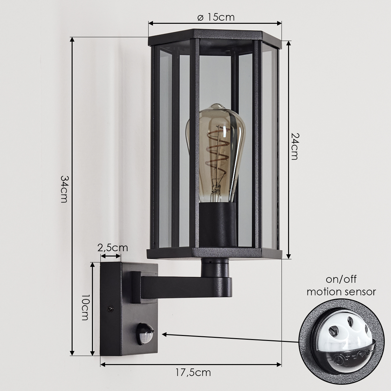 Schwarze Außenlampe mit Glasscheiben, einer Vintage-Glühbirne und einem Bewegungssensor, an einer weißen Wand montiert. Maße angegeben.