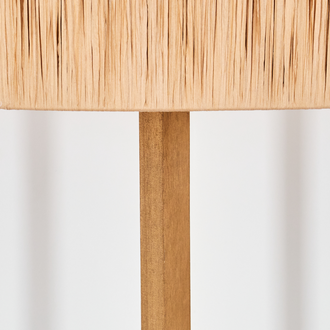 Nahaufnahme eines beigefarbenen Lampenschirms mit Holzstütze. Der Hintergrund ist schlicht weiß.