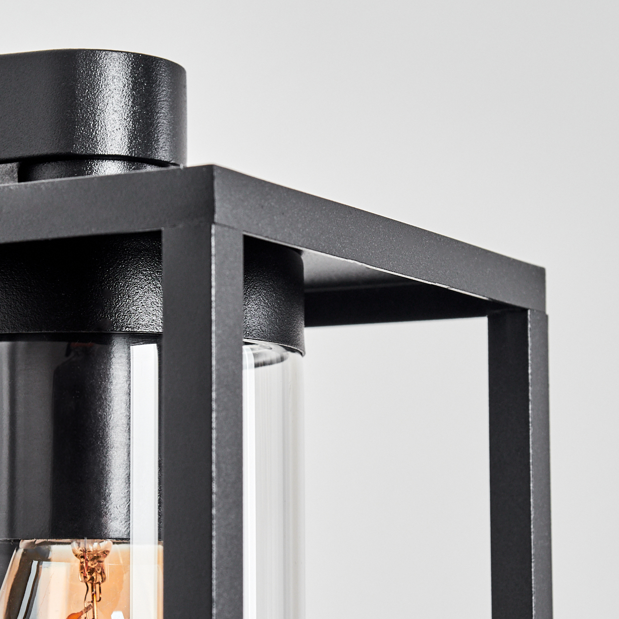 Nahaufnahme einer schwarzen Metalllaterne mit einem Glaszylinder. Der Hintergrund ist schlicht weiß.
