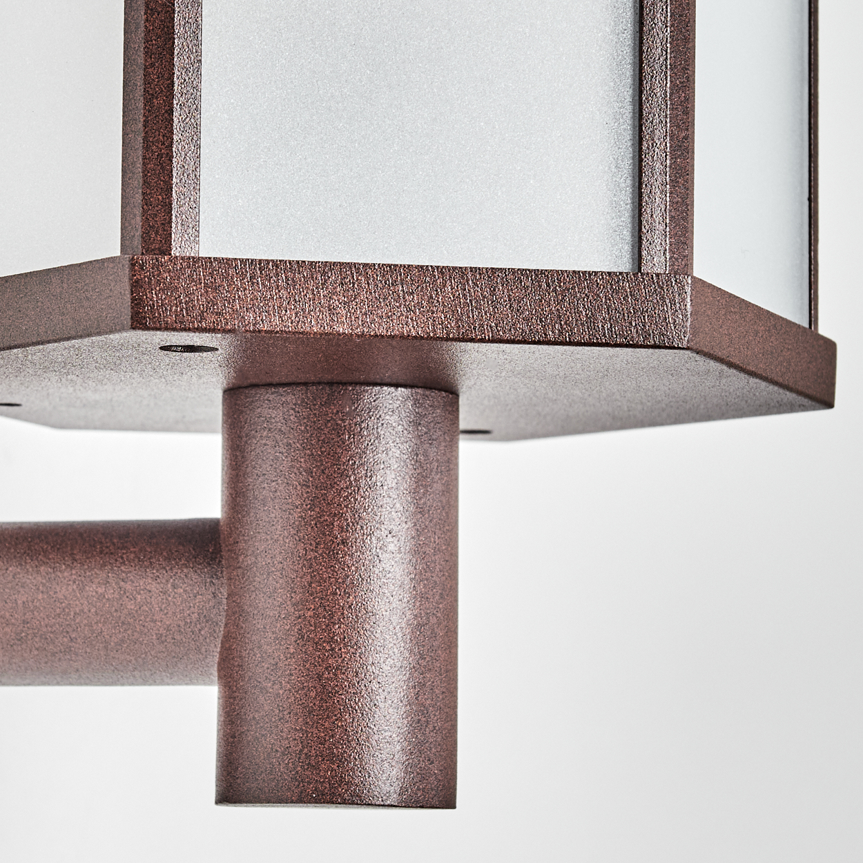 Nahaufnahme einer bronzefarbenen Außenlampe. Sie hat einen quadratischen Kopf mit Milchglas und einen zylindrischen Sockel, alles auf weißem Hintergrund.