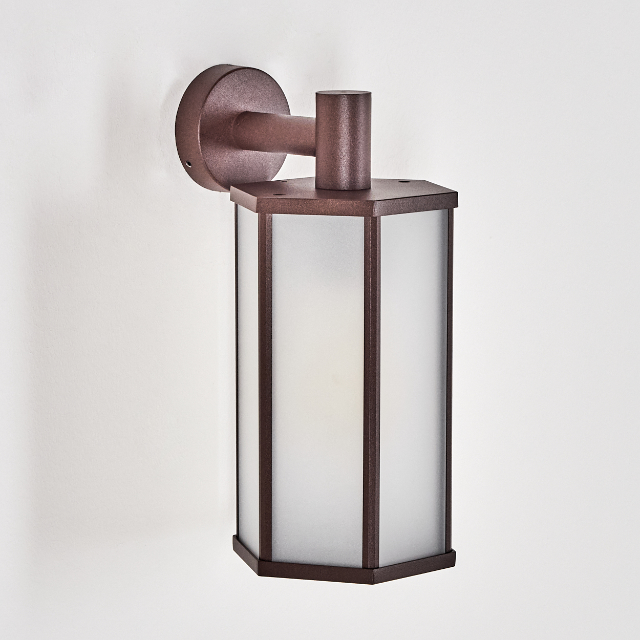 Eine bronzefarbene Außenwandleuchte. Sie hat einen Lampenschirm aus Milchglas mit bronzefarbenem Rand. An einer weißen Wand montiert.