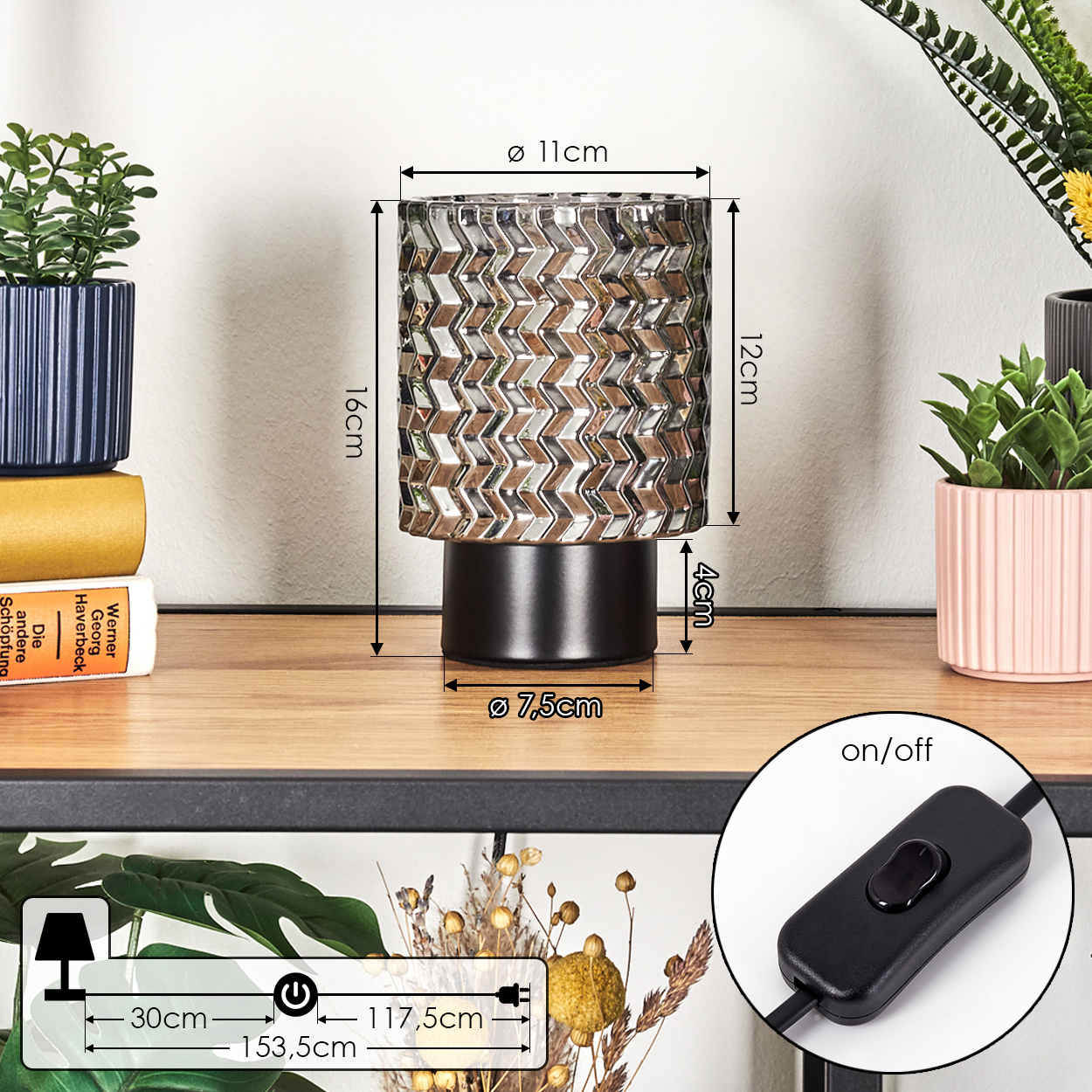 Eine dekorative Lampe mit gemustertem Schirm steht auf einem Regal. Pflanzen, Bücher und ein Schalter sind ebenfalls vorhanden.