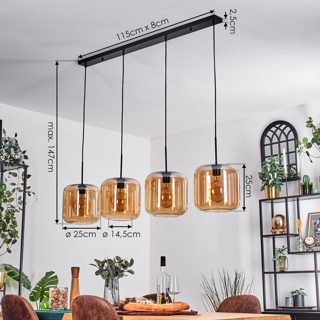 Vier bernsteinfarbene Glas-Hängeleuchten hängen über einem Holztisch. Maße sind angegeben. Pflanzen und ein schwarzes Regal sind im Hintergrund.