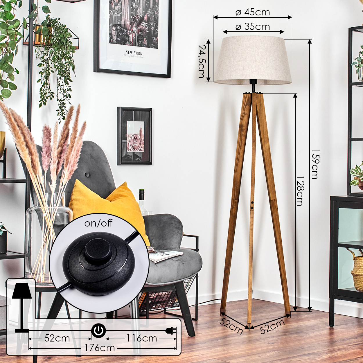 Eine hölzerne Stativ-Stehlampe mit beigem Lampenschirm steht in einem Wohnzimmer. Im Hintergrund sind ein grauer Sessel und Dekorationsartikel zu sehen.