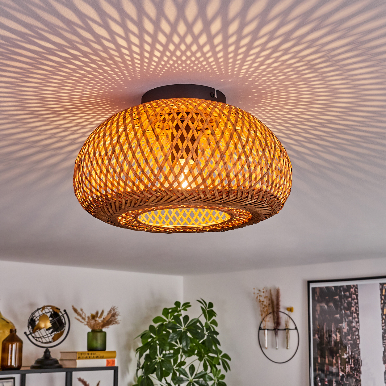 Eine Deckenlampe aus gewebtem Bambus wirft komplizierte Schatten. Darunter befindet sich ein Regal mit Dekoration, Globus, Büchern und Pflanzen.