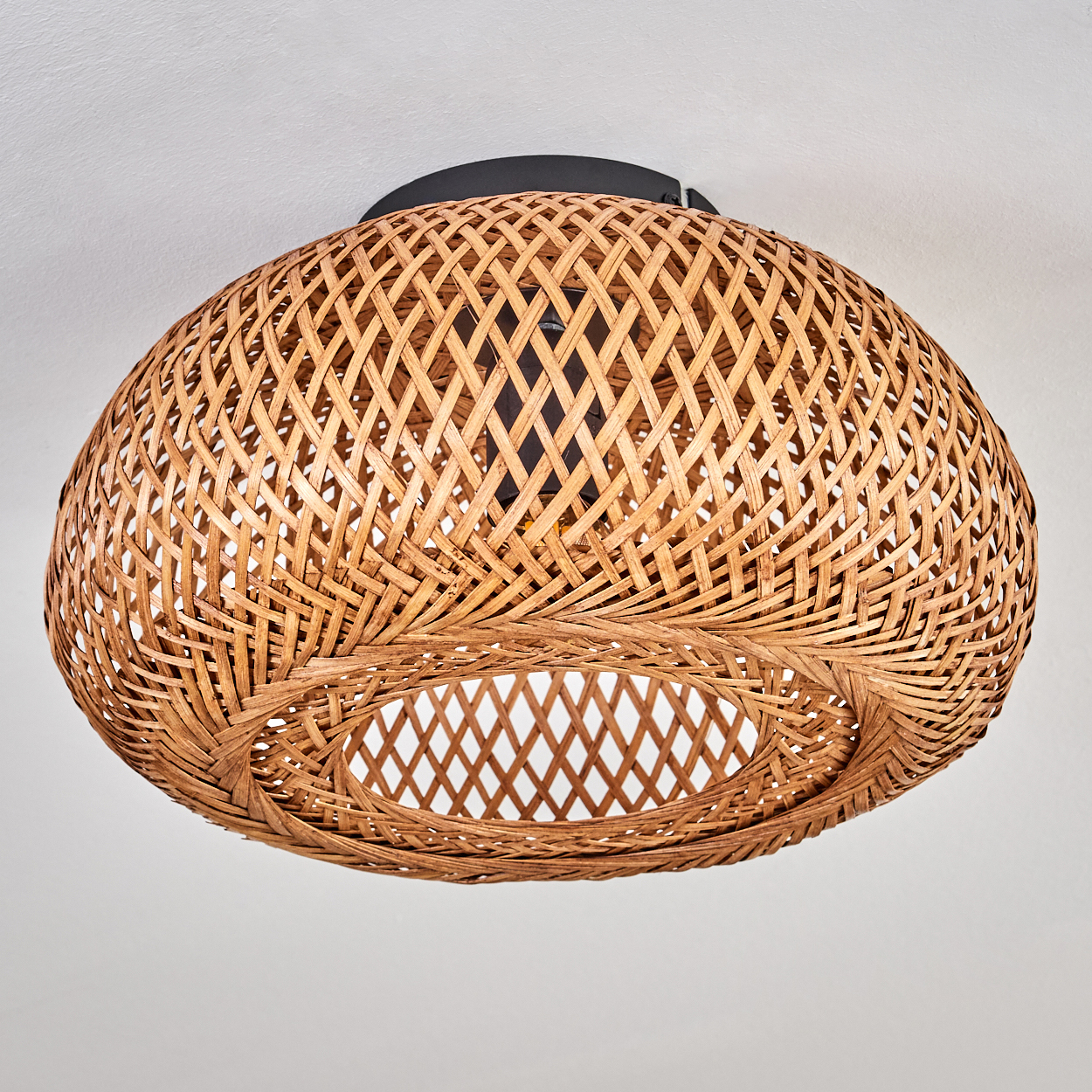 Eine gewebte Pendelleuchte aus Rattan hängt von einer weißen Decke. Das Licht ist kuppelförmig mit einer kreisförmigen Öffnung unten.